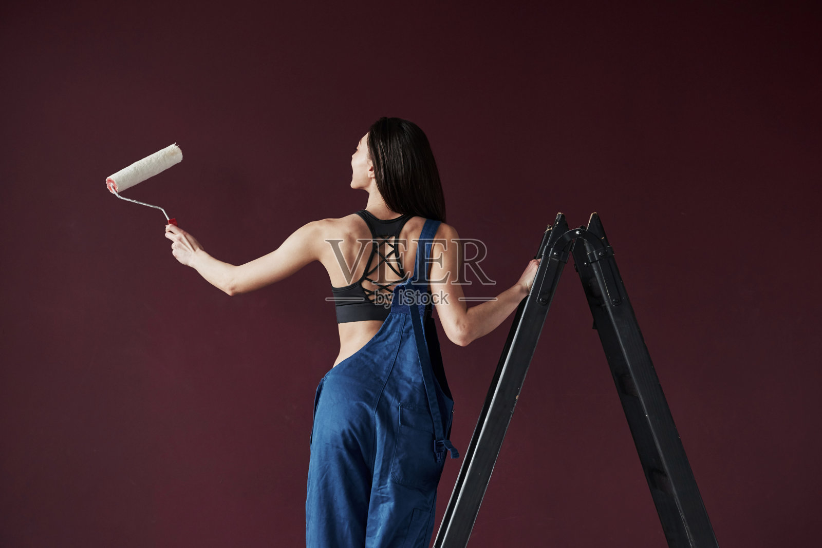 后面的观点。年轻的家庭主妇决定把墙纸粘在她新房子的房间里照片摄影图片