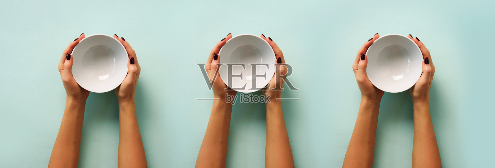 女性手拿白色空碗的图案在蓝色背景与复制空间。健康饮食、节食观念。横幅照片摄影图片