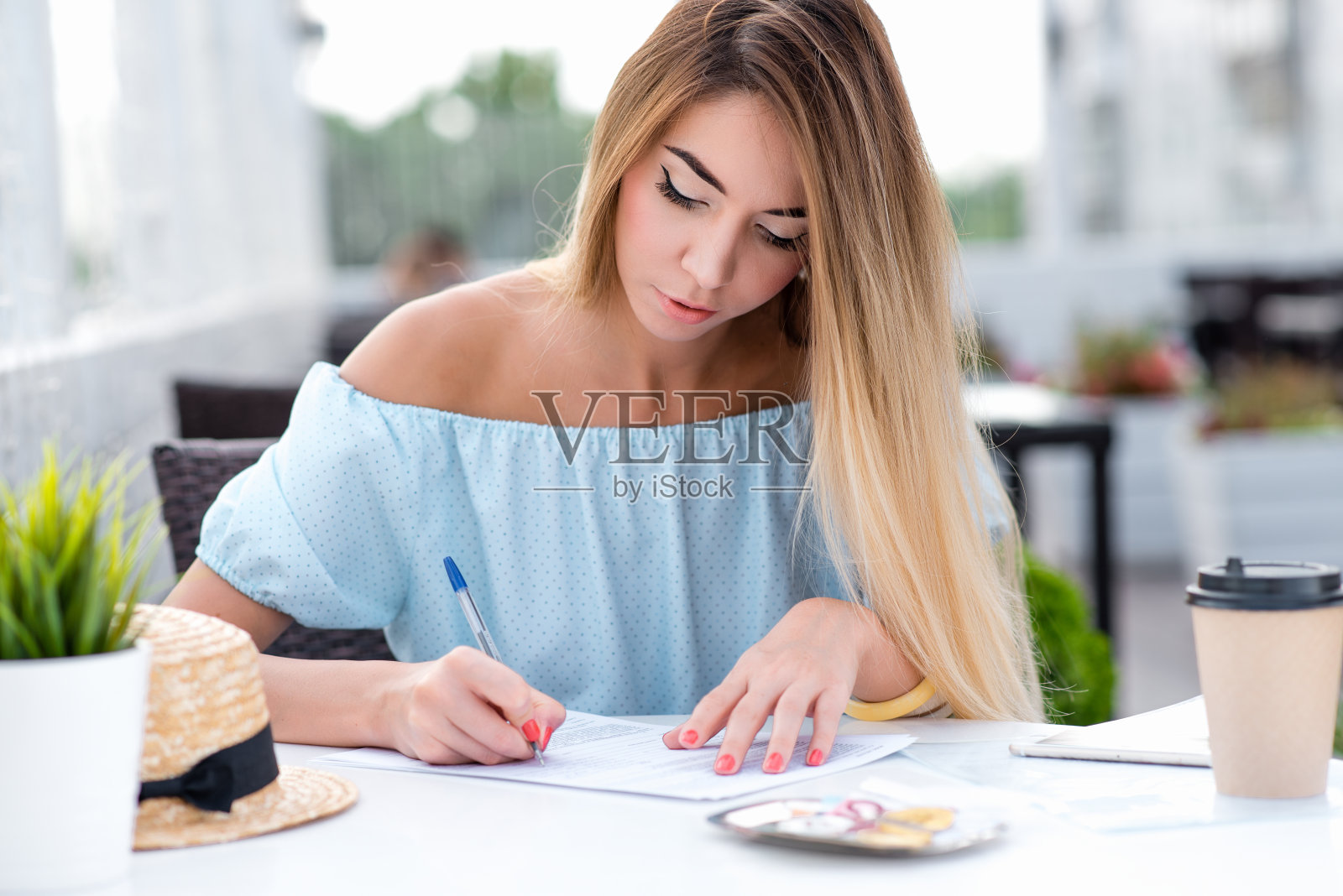 一个女商人，在一个夏天的咖啡厅里，填写一份书面合同，在合同上签字，进行交易，证明文件。法律服务，文书工作和文件。照片摄影图片