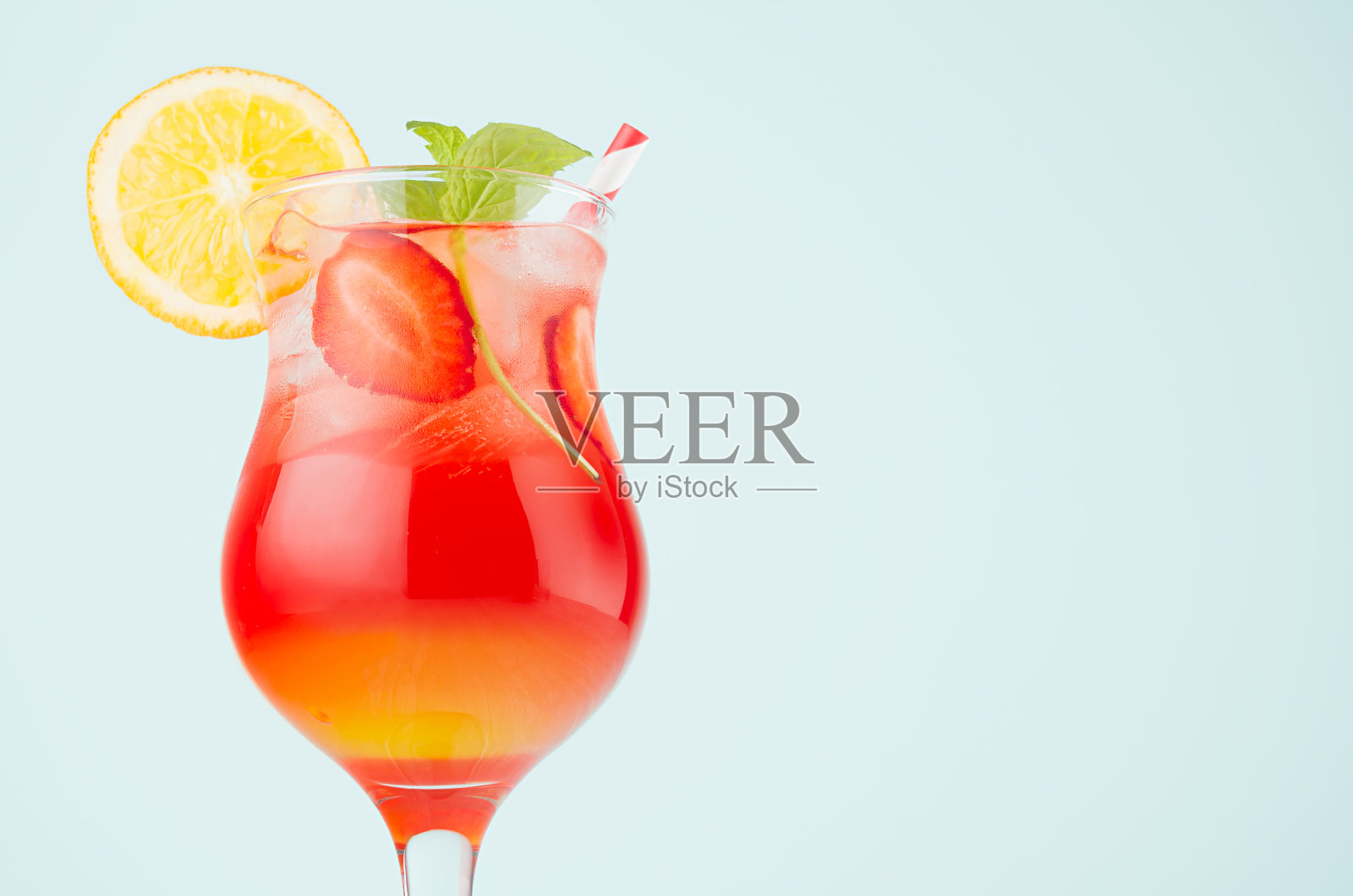 夏季新鲜条纹红色，黄色鸡尾酒与橙子，冰，草莓，薄荷在柔和的浅绿色背景，特写，顶部，边缘，细节。照片摄影图片