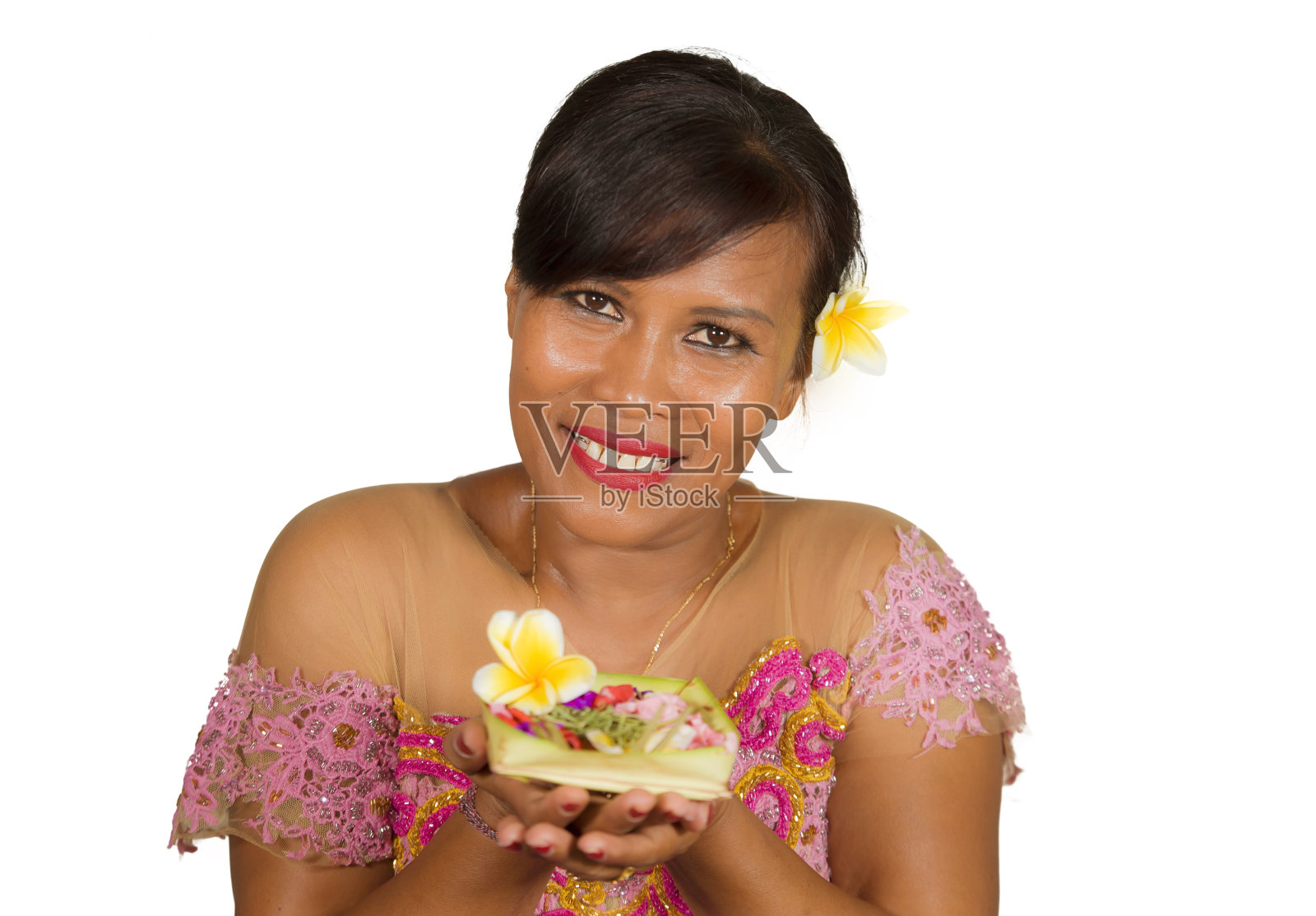 这是一幅美丽而幸福的印尼巴厘中年妇女的肖像画，她穿着传统的仪式服装，面带微笑，手里拿着鲜花，欢迎来到巴厘岛的印度教照片摄影图片