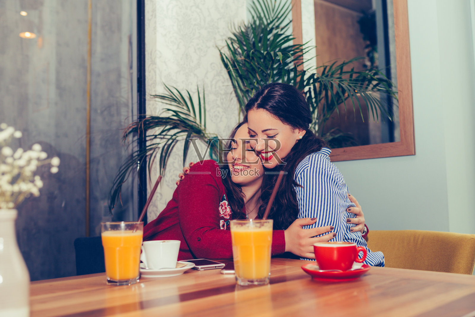 坐在咖啡馆里拥抱最好的朋友的快乐女士照片摄影图片
