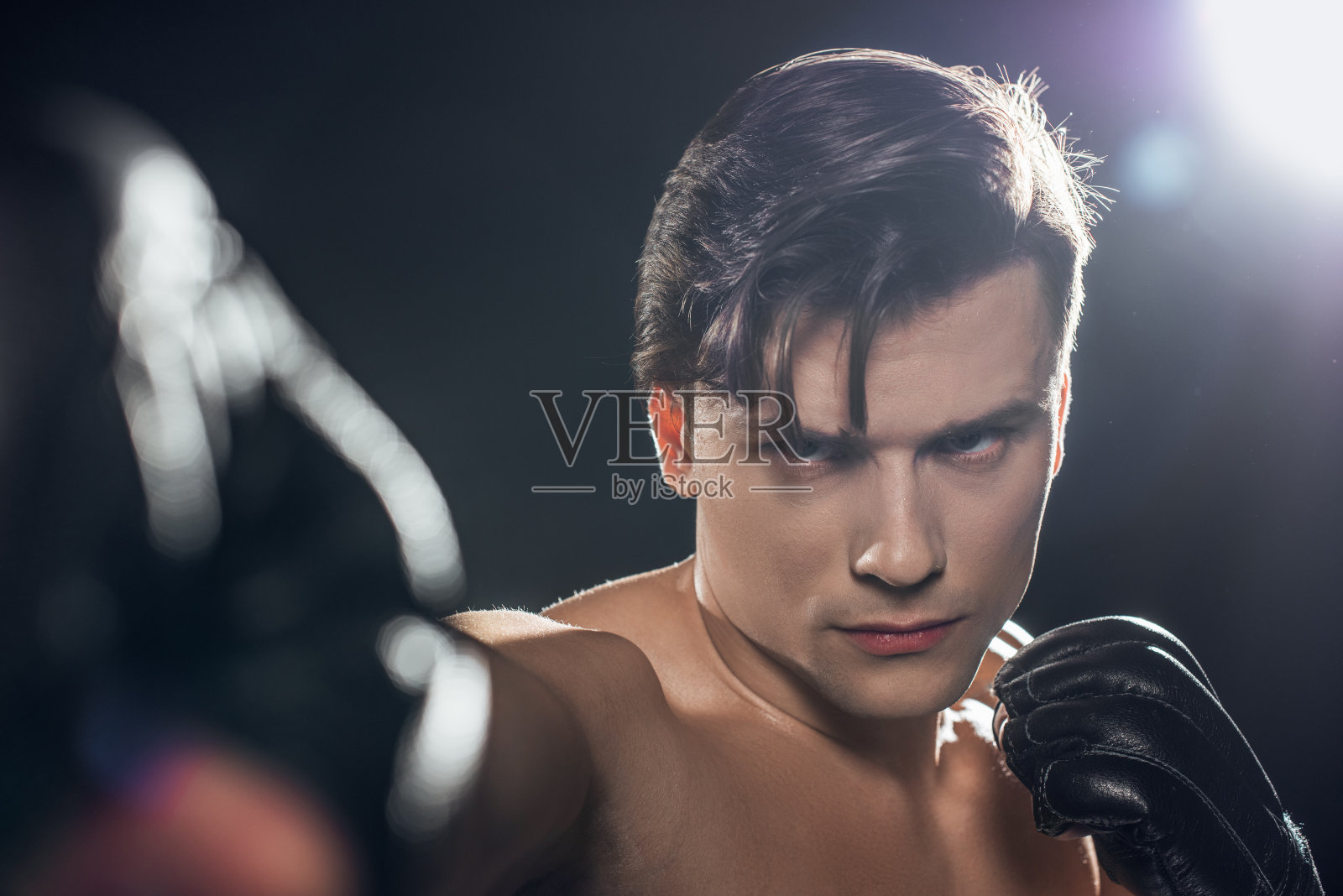 集中拳手在拳击手套训练中有选择的聚焦，并在黑色上看摄像机照片摄影图片