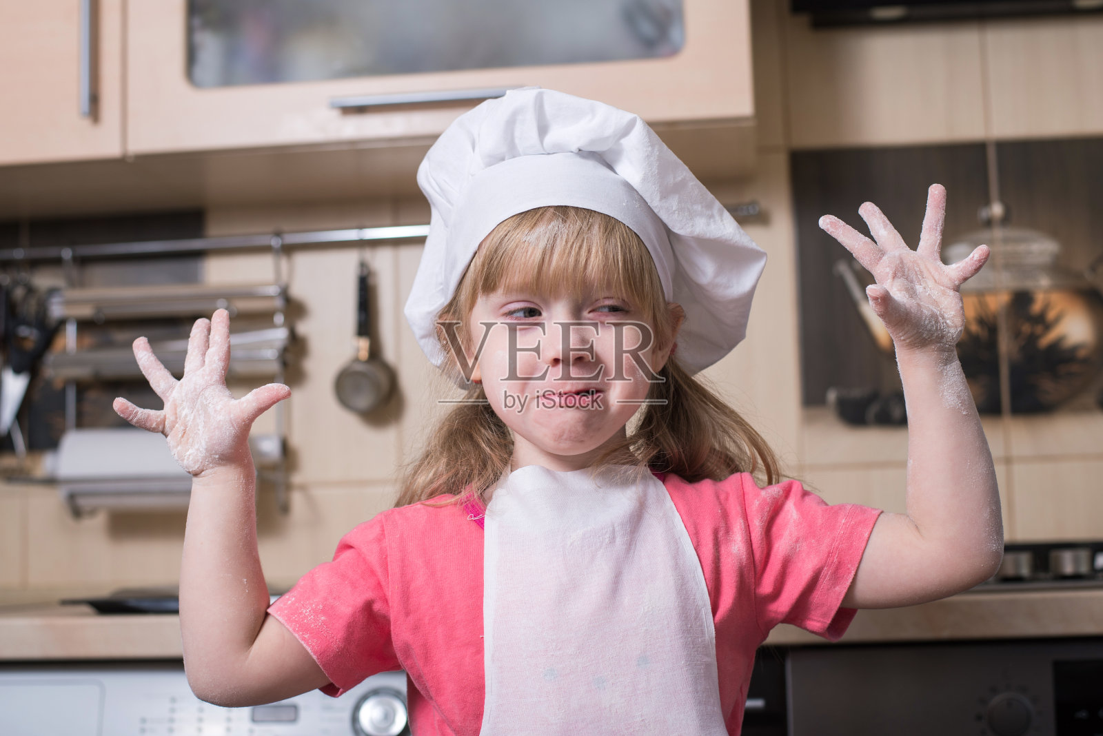 厨房里戴着厨师帽的小面包师。照片摄影图片