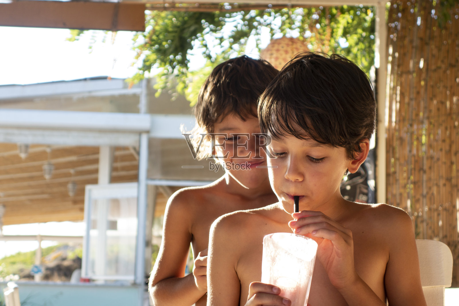 兄弟男孩在海滩上喝奶昔鸡尾酒照片摄影图片