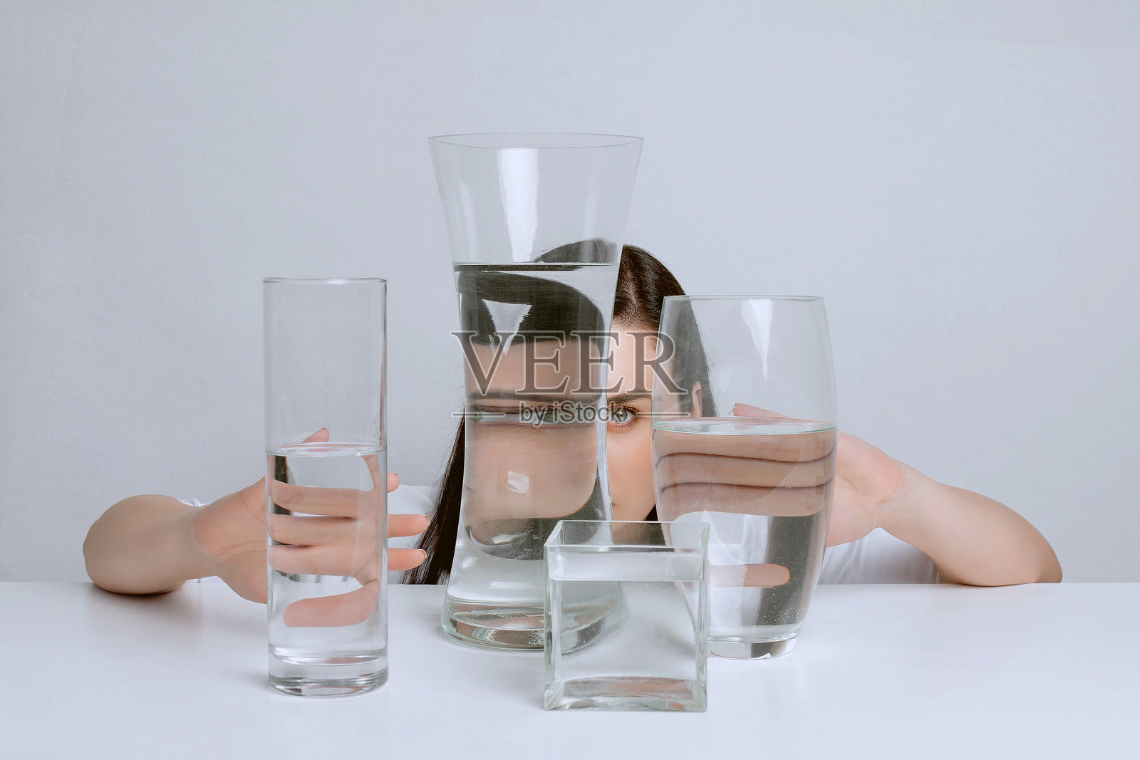 年轻迷人的女人的艺术肖像。水在玻璃花瓶中的扭曲反射。照片摄影图片