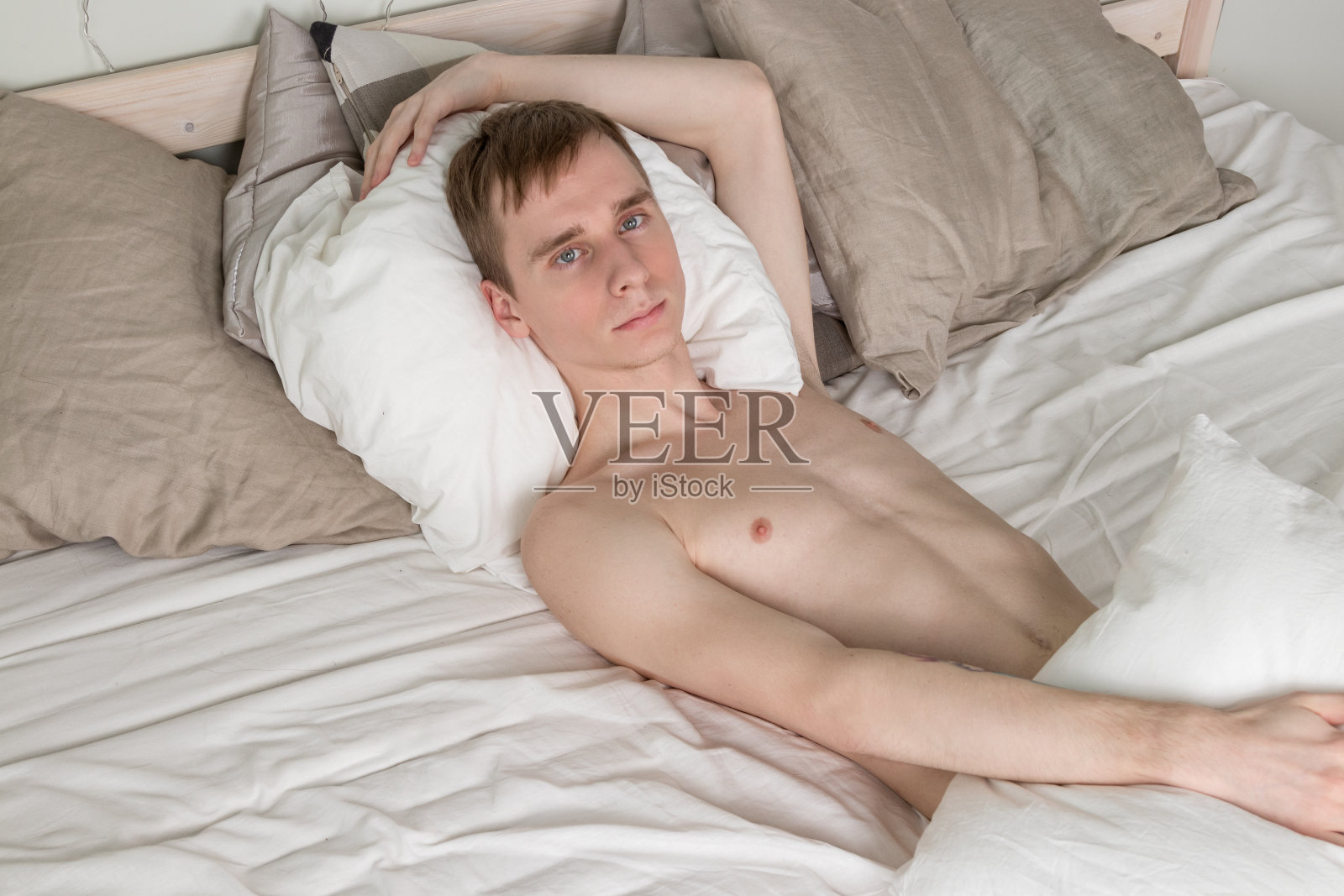 英俊的年轻人在床上睡觉。性感裸男正在休息照片摄影图片