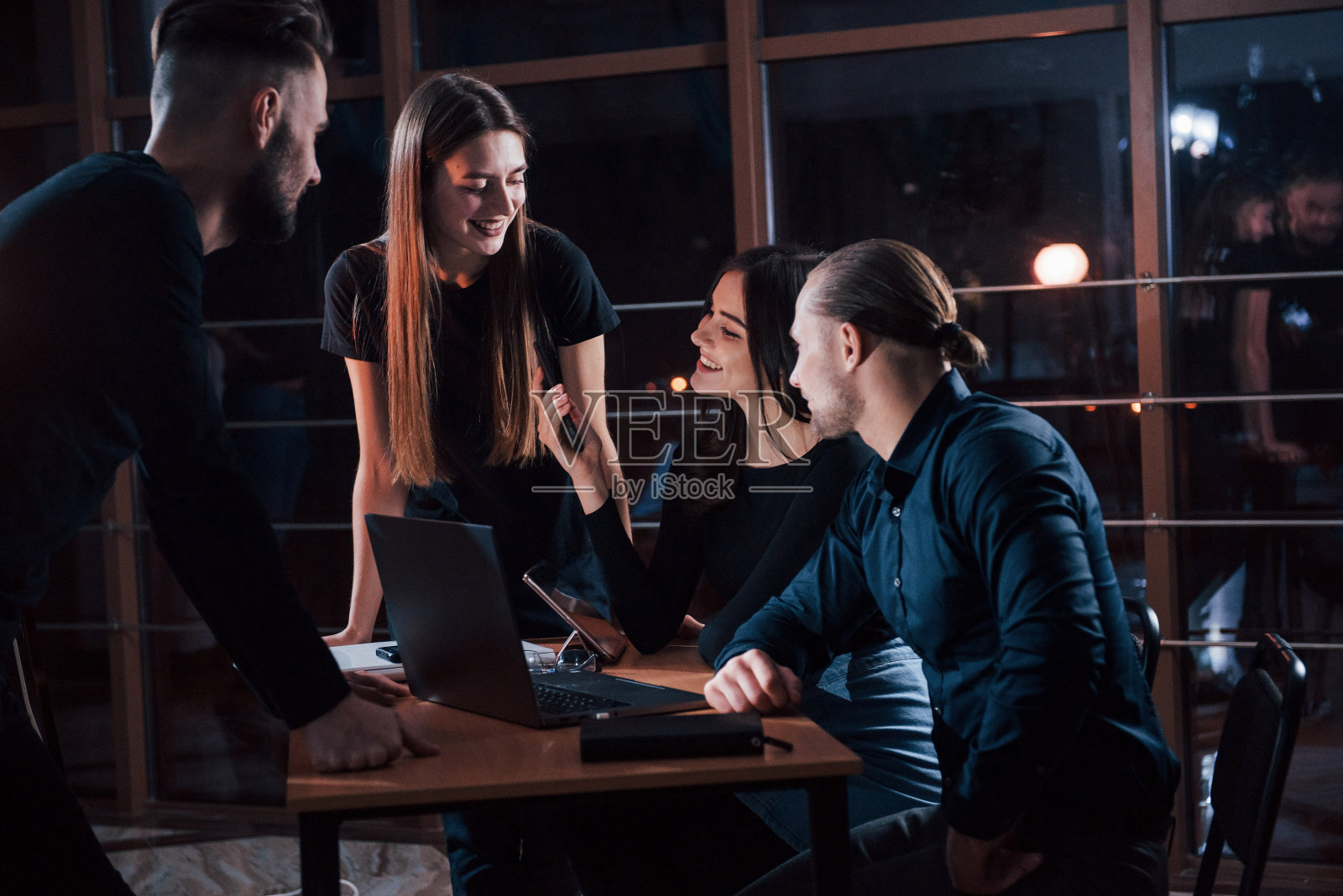 他说什么了?一群年轻的商人晚上在办公室里为他们的项目工作照片摄影图片