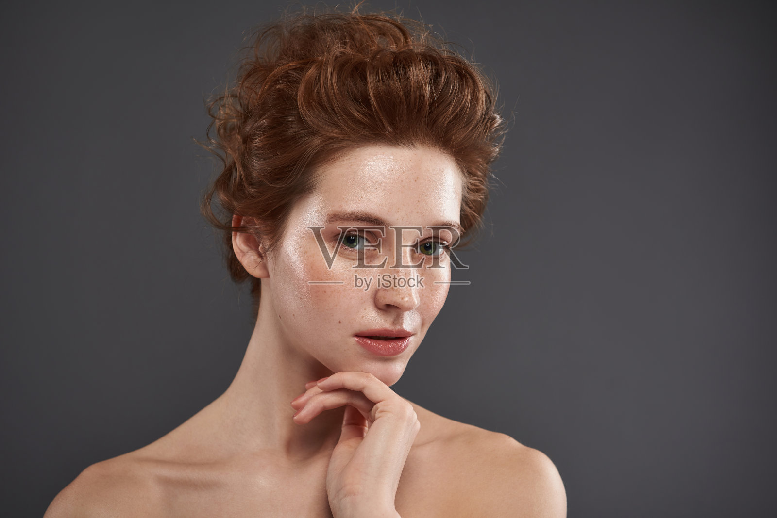 迷人的红头发女孩，脸上有雀斑，手托着下巴照片摄影图片