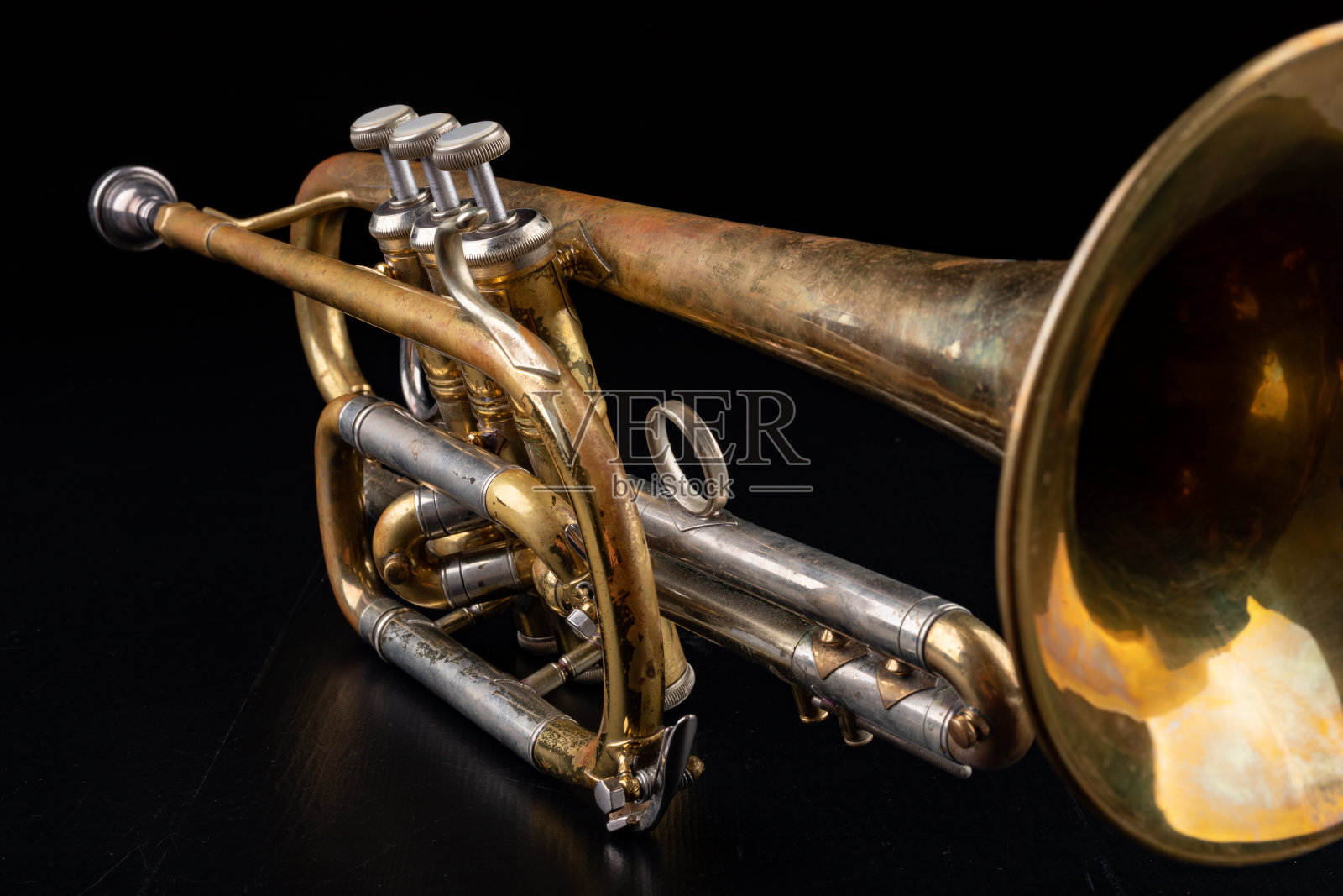 深色木桌上放着一把旧小号。老式管乐器。黑色背景。照片摄影图片