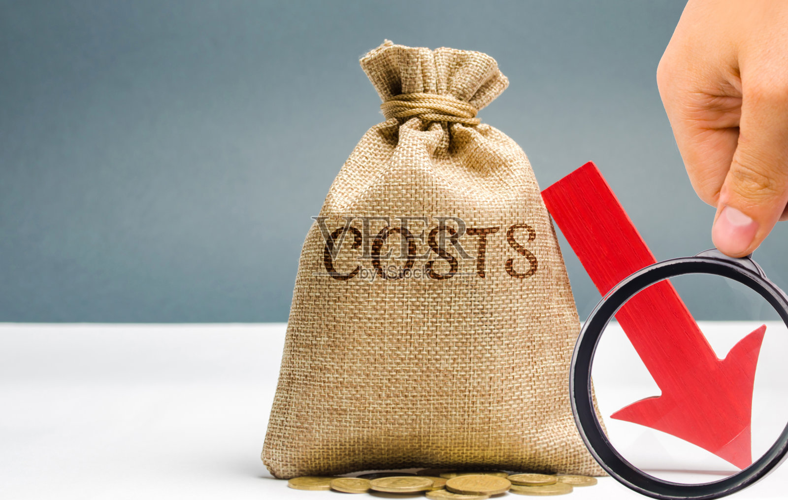 钱袋里的硬币上写着成本和一个向下的箭头。减少。费用减少。商业和金融的概念。金钱管理。预算计划。收入分析。资金分配照片摄影图片