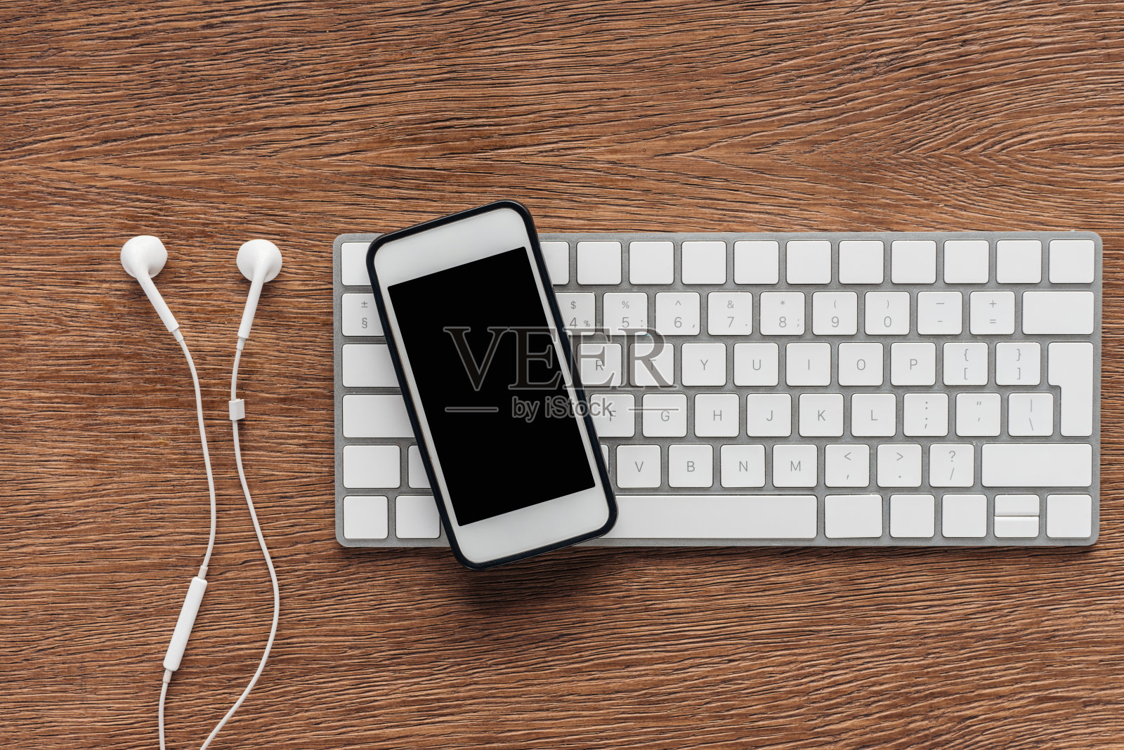 俯视图键盘，智能手机与空白屏幕和耳机在木制背景照片摄影图片