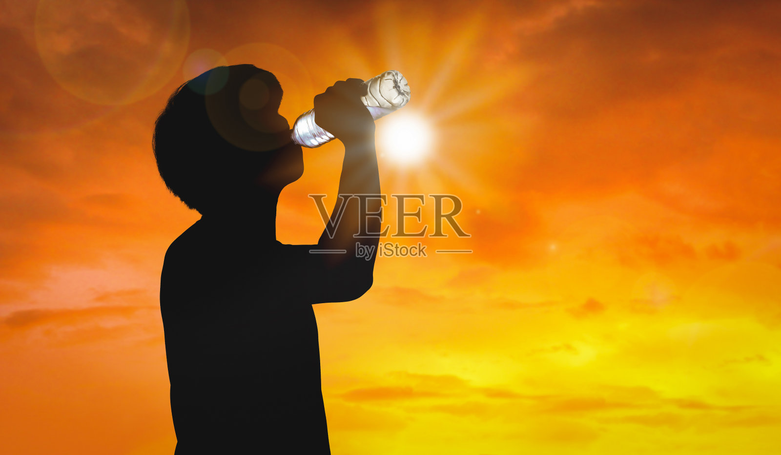 剪影男子正在饮用水瓶在炎热的天气背景下与夏季。高温和热浪概念。照片摄影图片