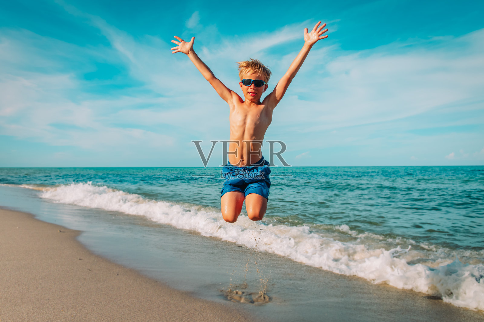 快乐的小男孩在沙滩上玩耍，孩子享受假期照片摄影图片