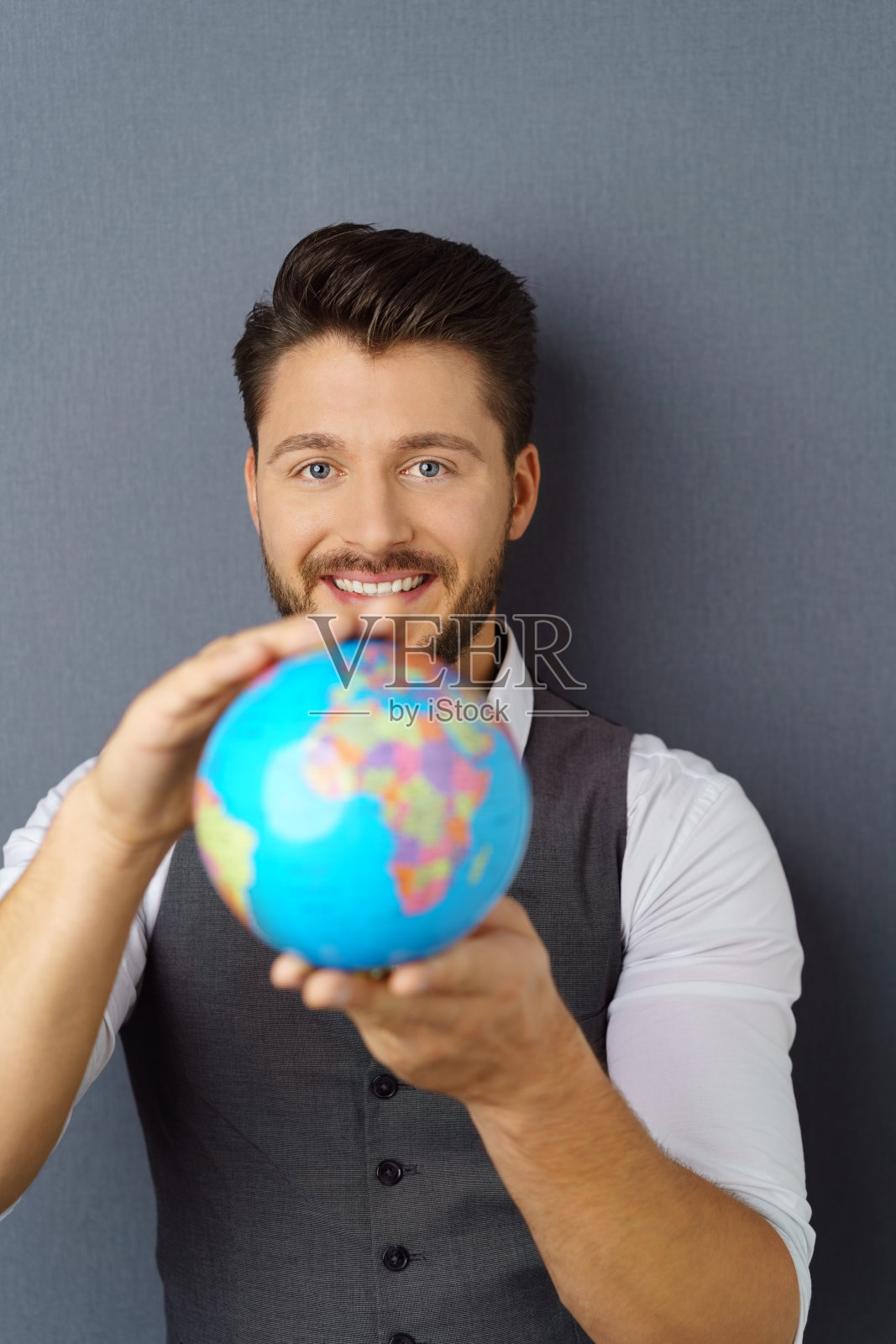 年轻优雅的胡子男人拿着地球仪照片摄影图片