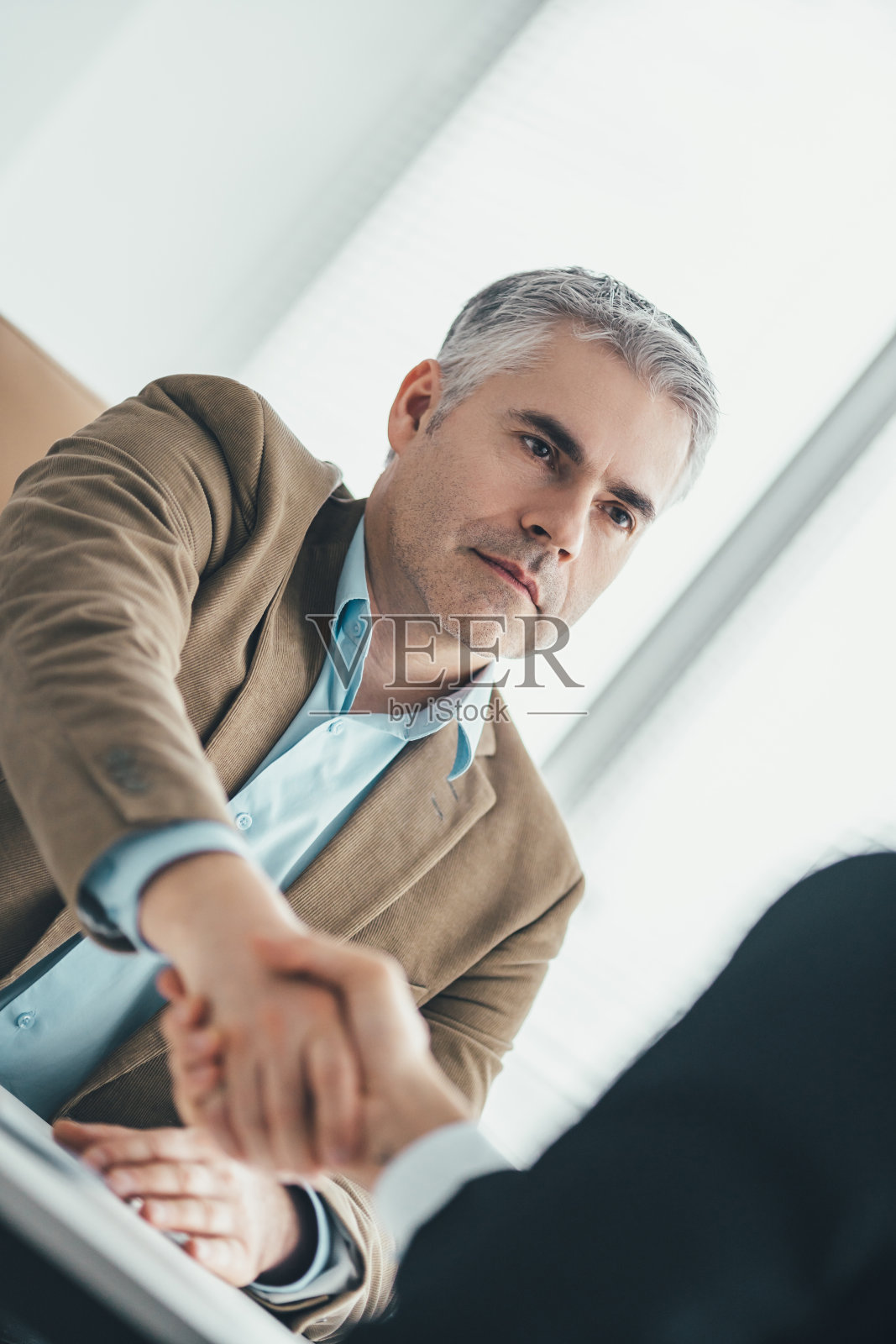 那两个商人在办公室里握手照片摄影图片