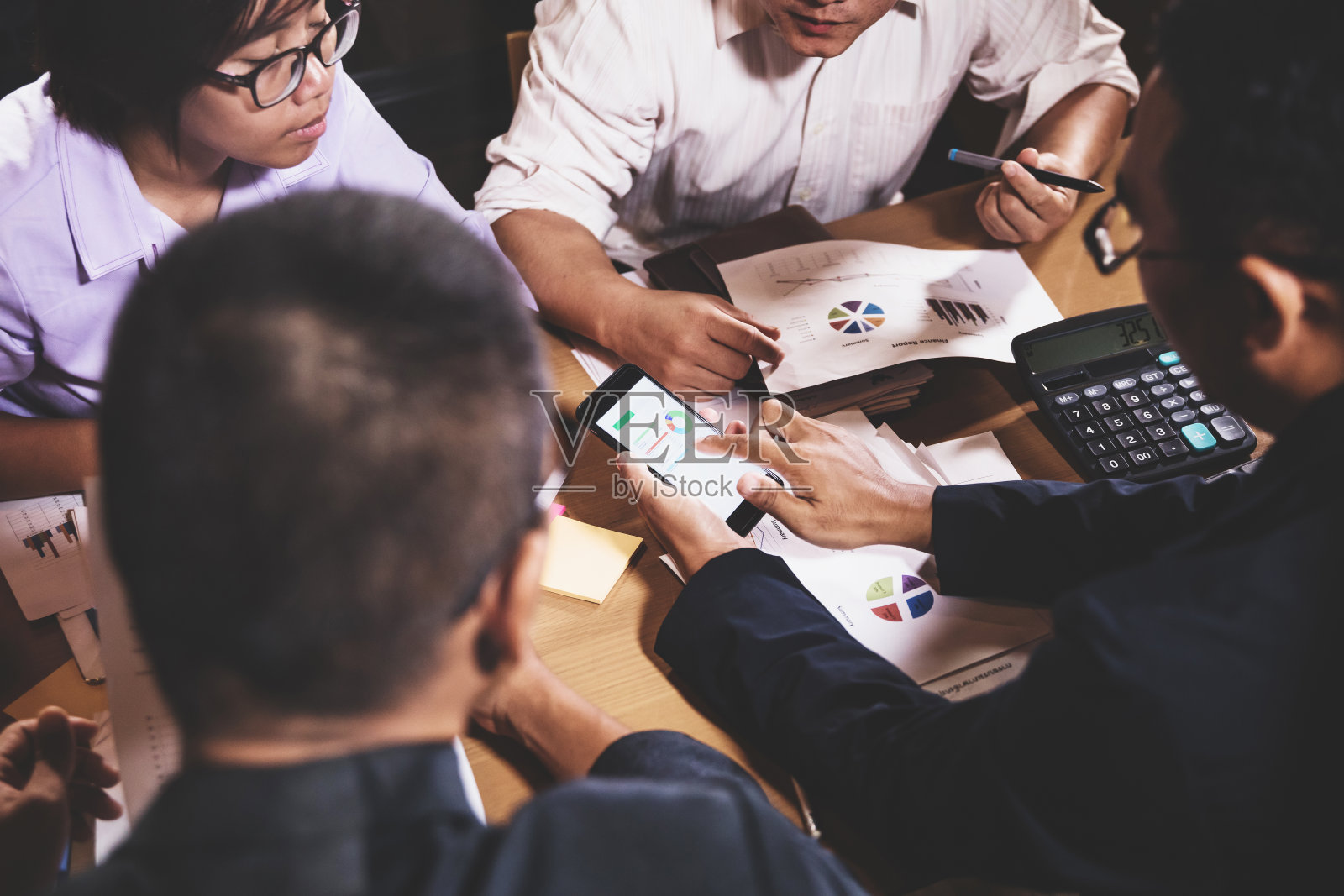 商务人士坐在办公室会议室讨论工作夜景，图表分析和团队合作概念照片摄影图片