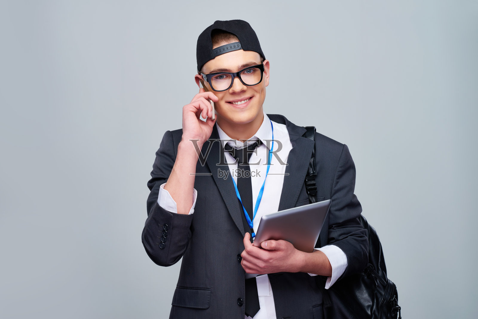 穿着西装的开朗学生在电话上讲话照片摄影图片
