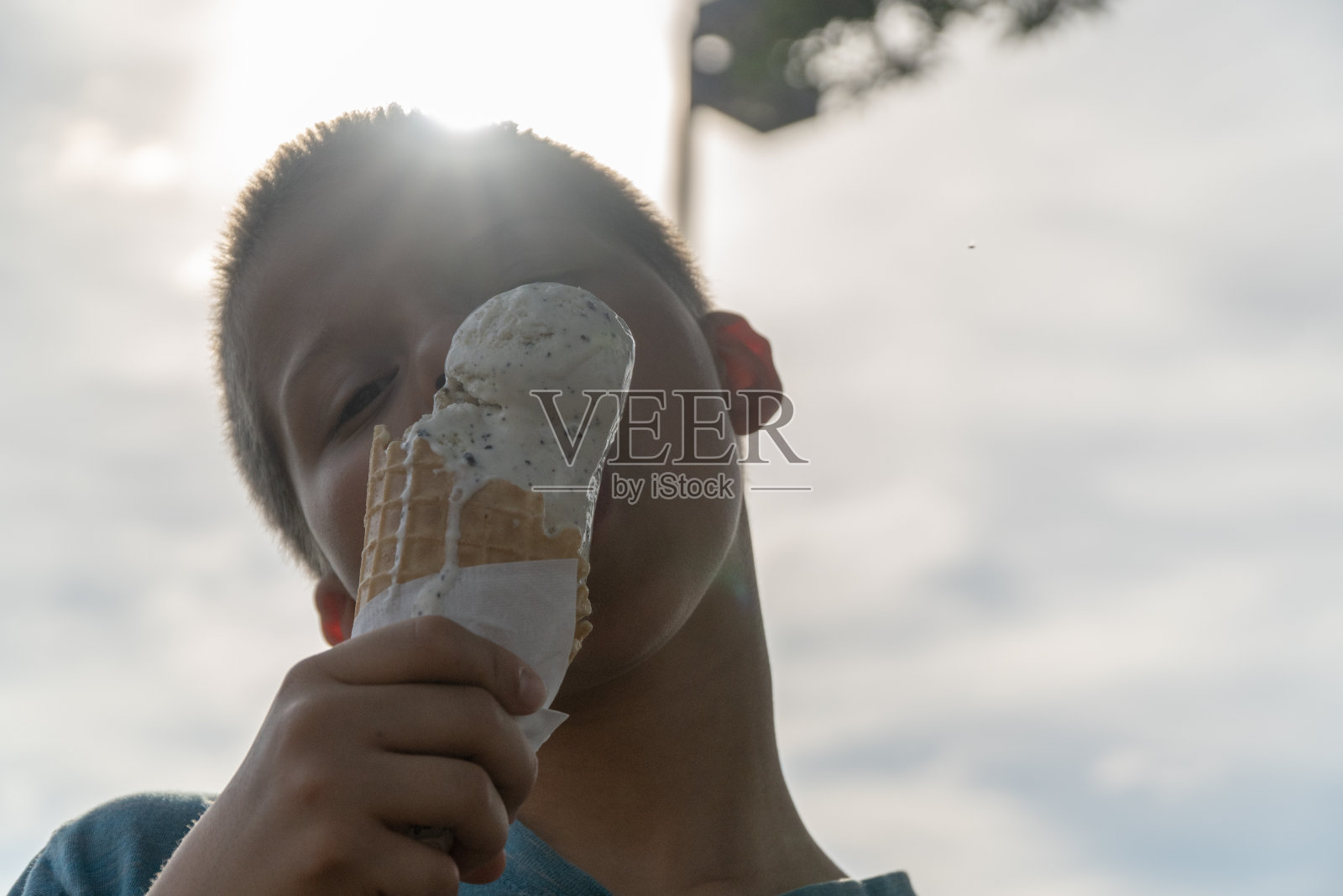 男孩在吃华夫蛋筒上的冰淇淋。照片摄影图片