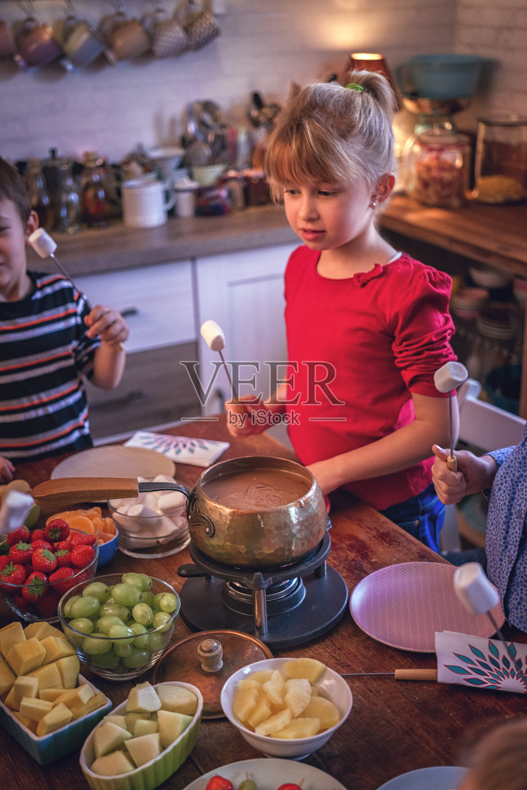 年轻家庭享用美味的巧克力火锅和水果照片摄影图片