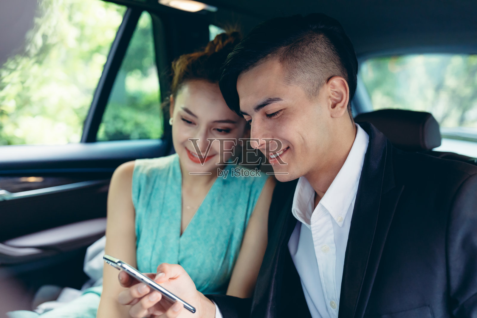 商人和女商人在汽车后座上使用智能手机。照片摄影图片