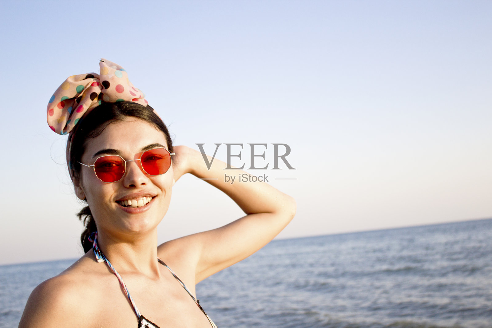 美丽微笑的女人看着相机在海滩上。照片摄影图片