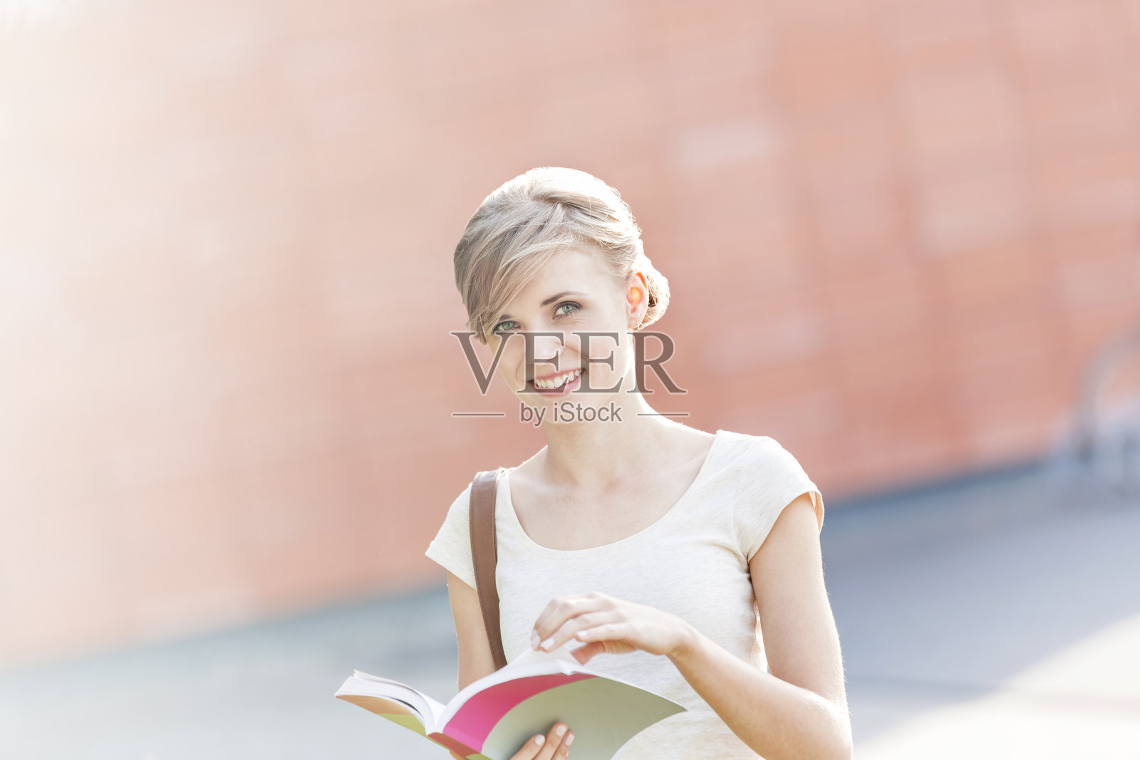 微笑的年轻女子与书在校园的肖像照片摄影图片