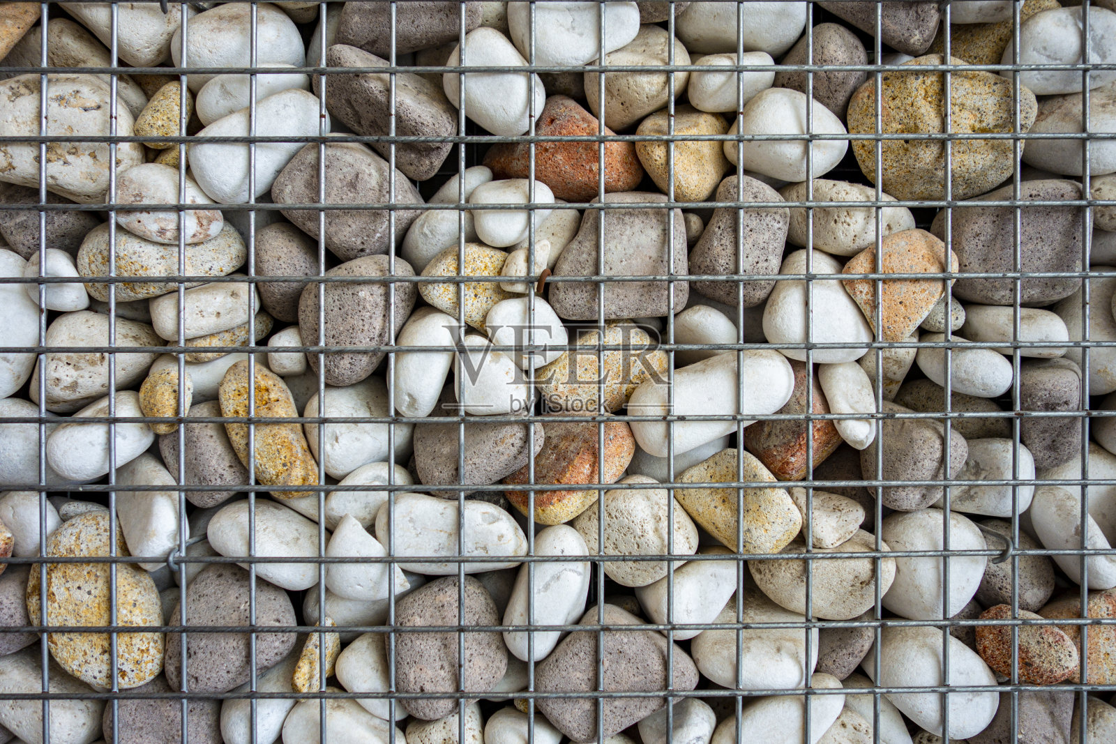 石头和鹅卵石在铁丝网墙照片摄影图片