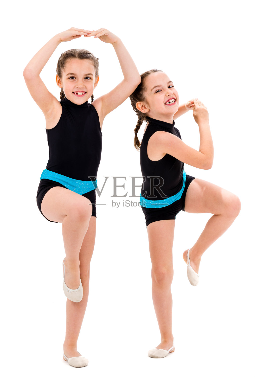 双胞胎女孩在白色背景下练习艺术体操。照片摄影图片