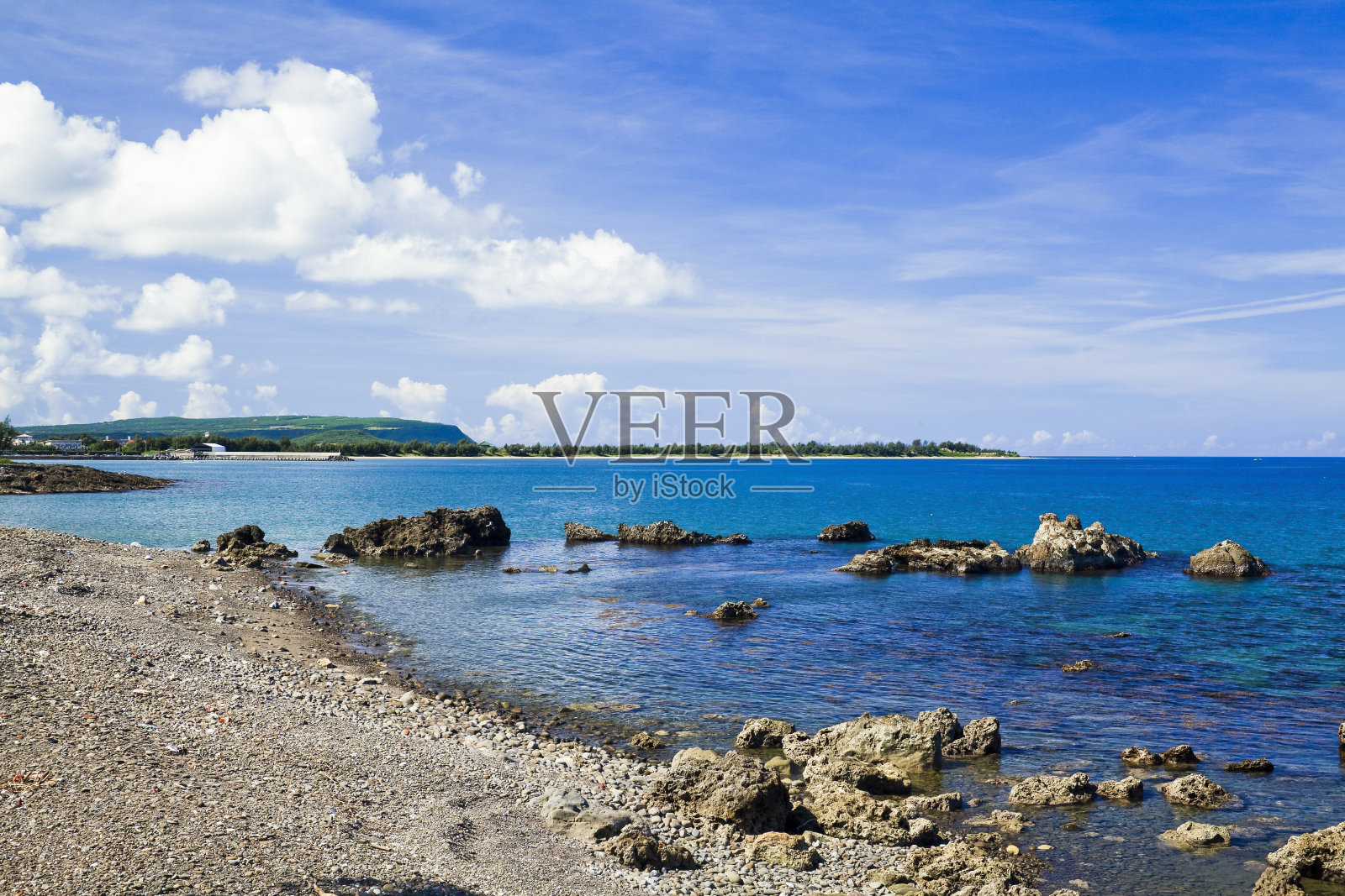 海岸边的礁石和海浪伴着蔚蓝的天空。照片摄影图片