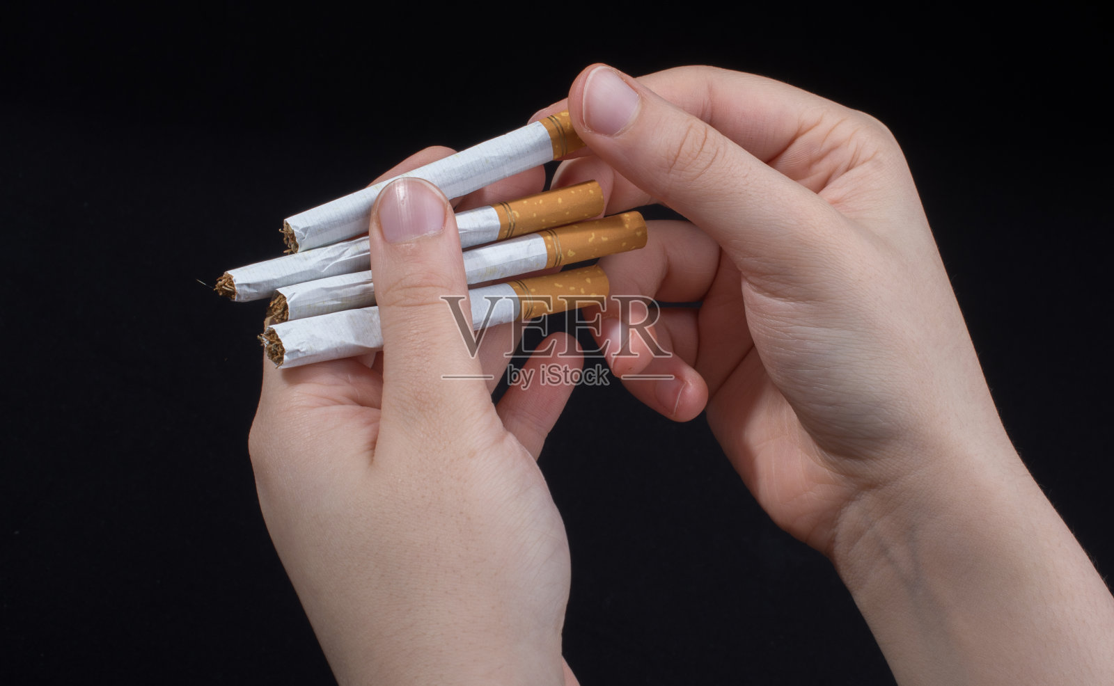 黑色背景上的手拿着香烟照片摄影图片