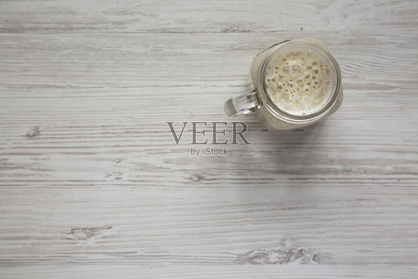 香蕉冰沙在一个玻璃罐子在白色的木制背景，俯视。平躺，俯视图，从上面。副本的空间。照片摄影图片