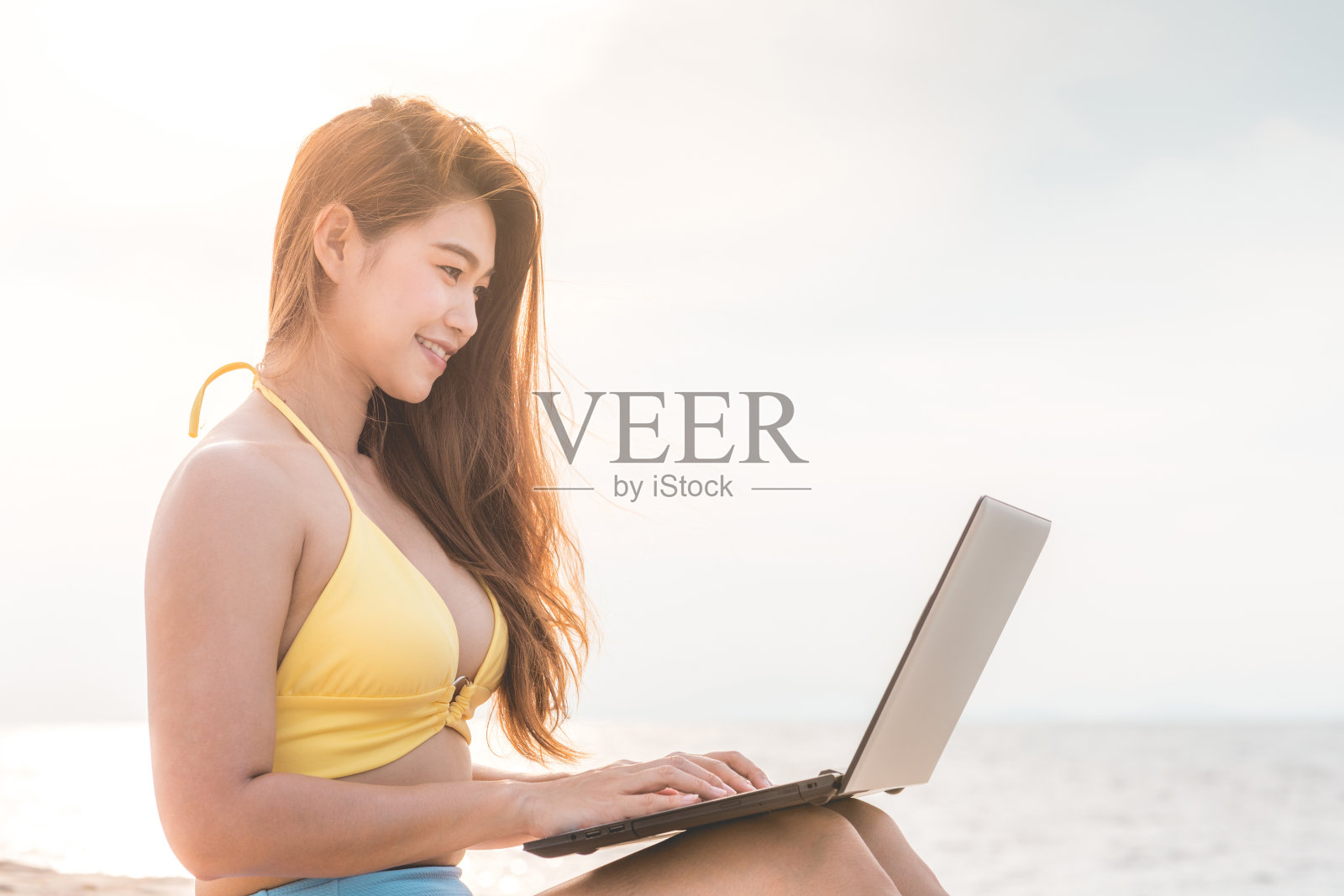 可爱的亚洲女人与电脑笔记本电脑在热带岛屿的海滩上工作与日落的感觉如此幸福和舒适，暑假和自由职业者的概念照片摄影图片