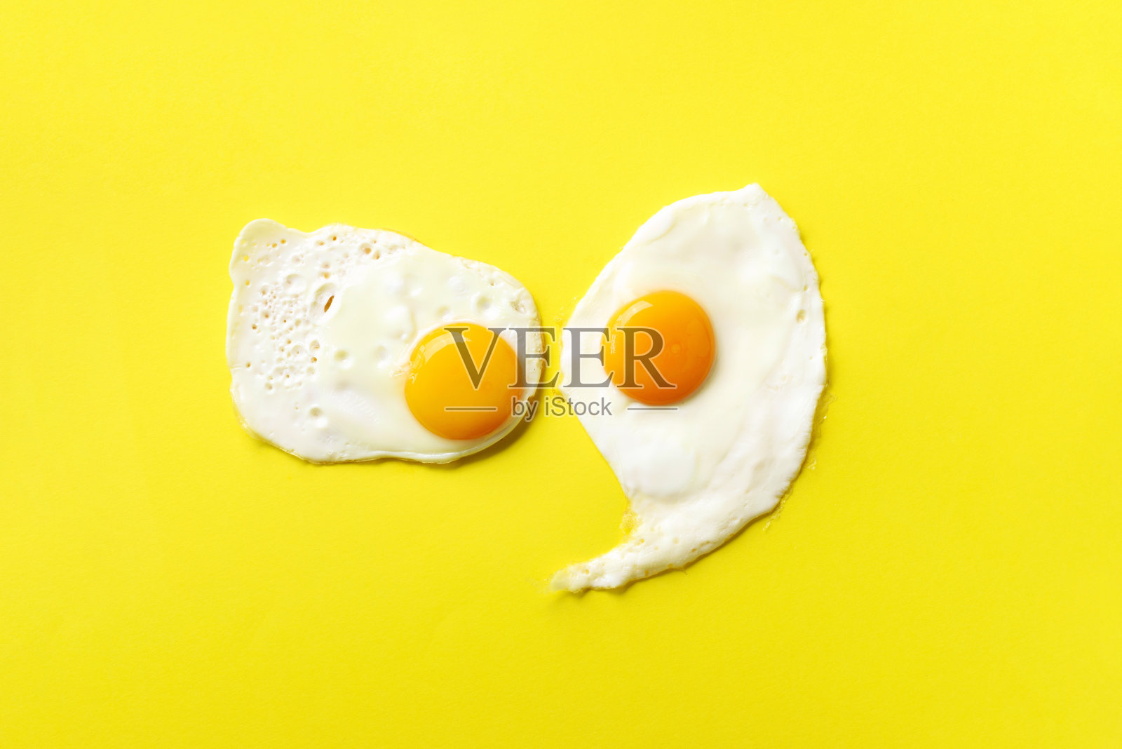 黄纸背景上的两个煎蛋。极简风格的创意食物概念。俯视图照片摄影图片