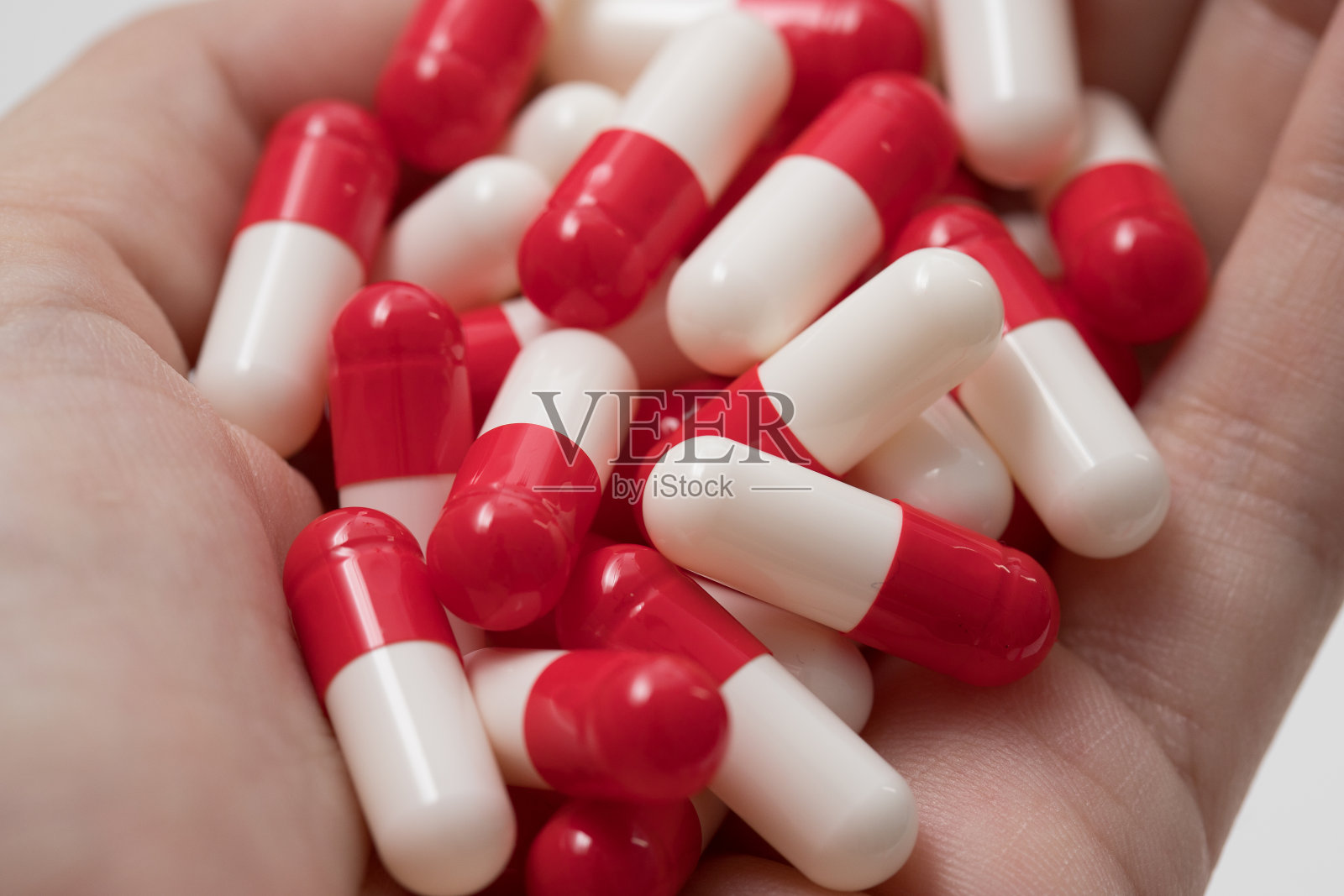 健康。女人手里拿着药。红白相间的胶囊。制药药剂。药物。照片摄影图片
