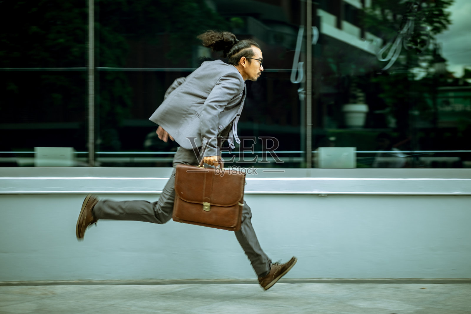 穿西装的人拿着一个皮包。他跑得很快。用动作技术摄影。照片摄影图片
