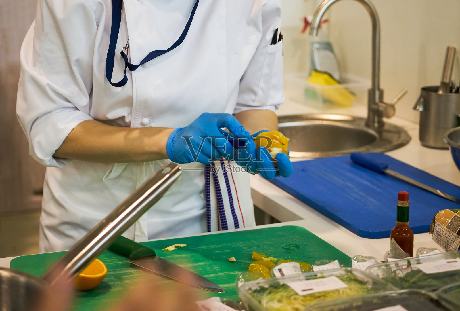 厨师手在切菜板上切橘子，特写。照片摄影图片