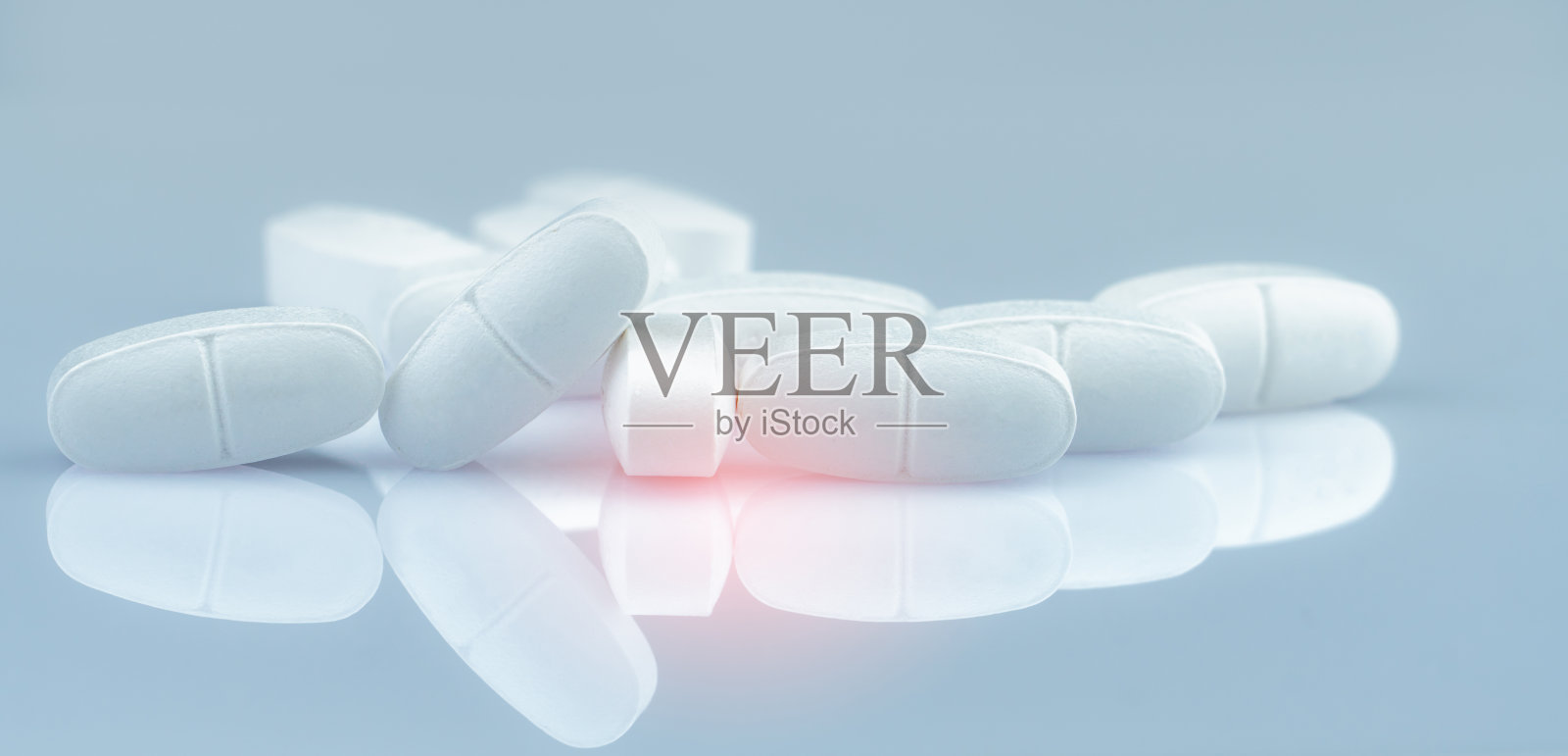 白色长方形药片堆在梯度背景上。白色抗生素药片。制药行业。药店的产品。药房、药店或医院的药品。抗生素耐药性。照片摄影图片