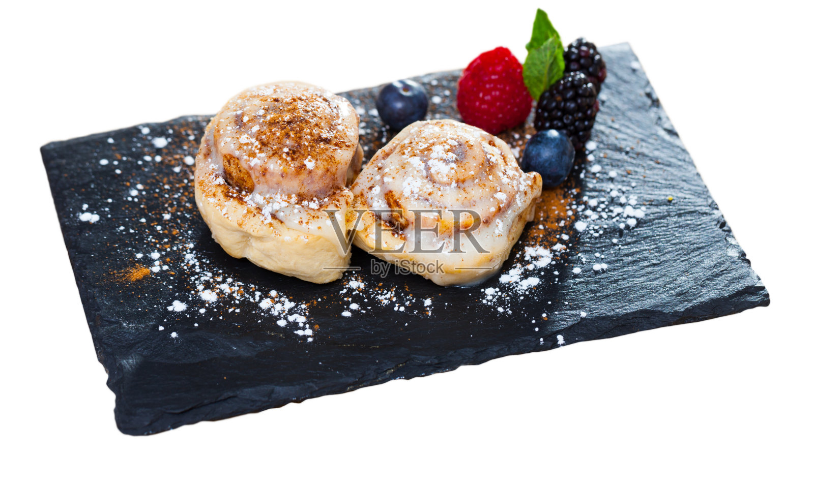 甜肉桂卷，糖粉和浆果在盘子里照片摄影图片