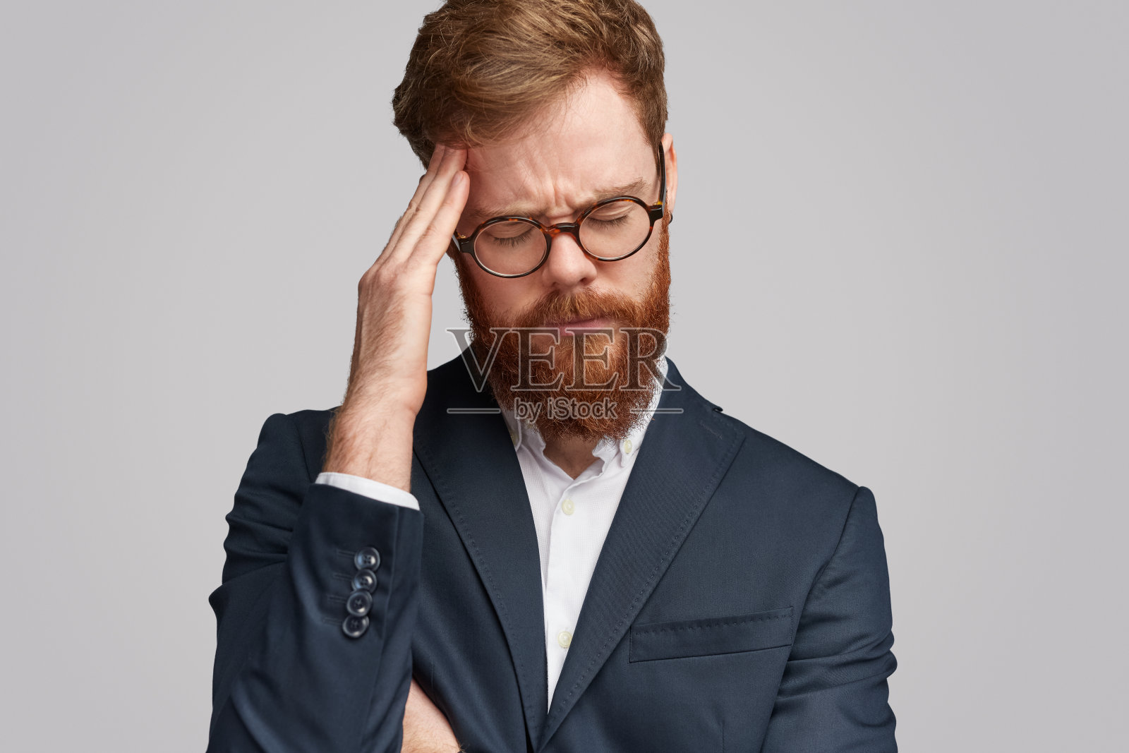 紧张的红胡子商人揉着前额照片摄影图片