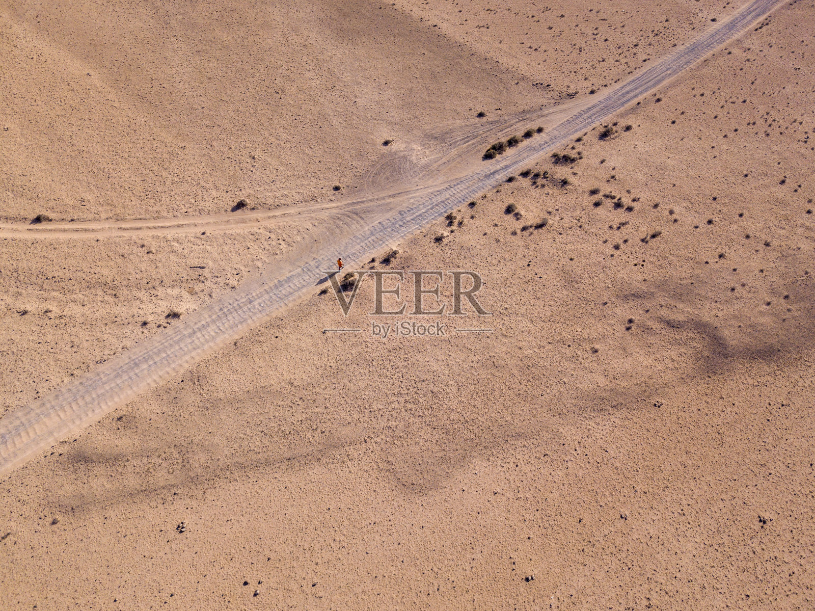 鸟瞰图沙漠景观兰萨罗特岛，加那利群岛，西班牙。一个穿着橙色t恤的男人走在沙漠里照片摄影图片