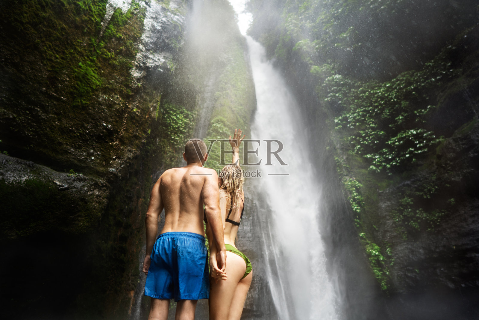 一对相爱的情侣在巴厘岛丛林的瀑布上摆姿势照片摄影图片