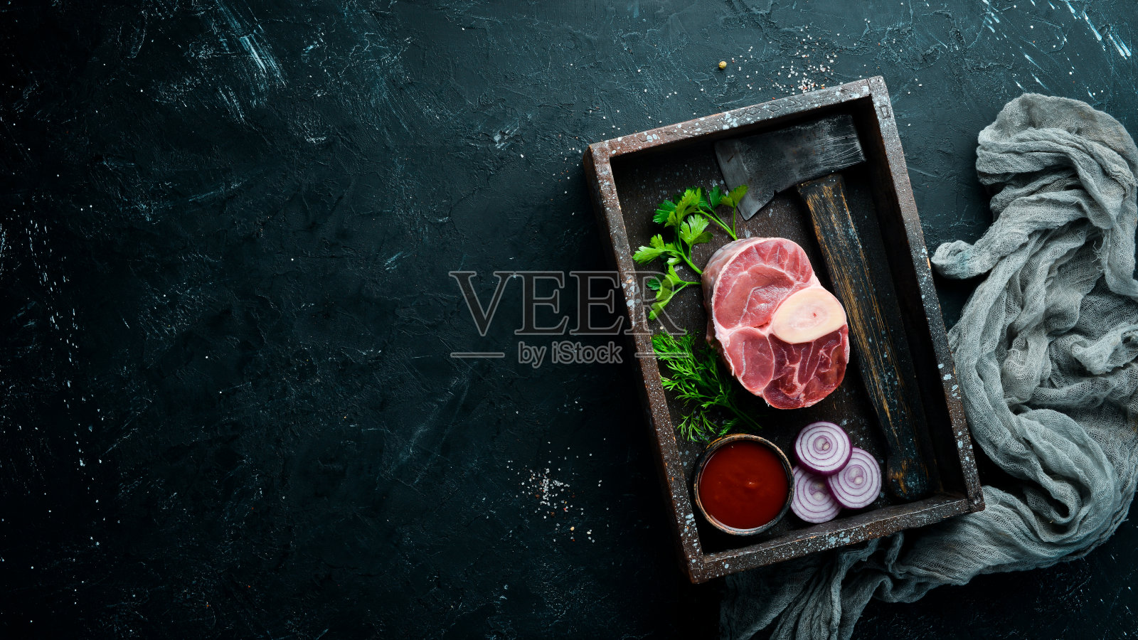 在黑色的背景上用香料和香草制作烩牛膝的新鲜的横切小牛小腿。前视图。为你的文本留出空间。照片摄影图片