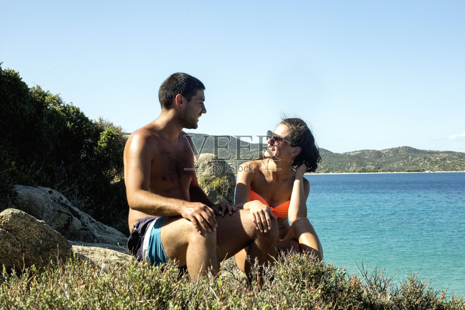 一对可爱的情侣在阳光明媚的海滩上聊天照片摄影图片