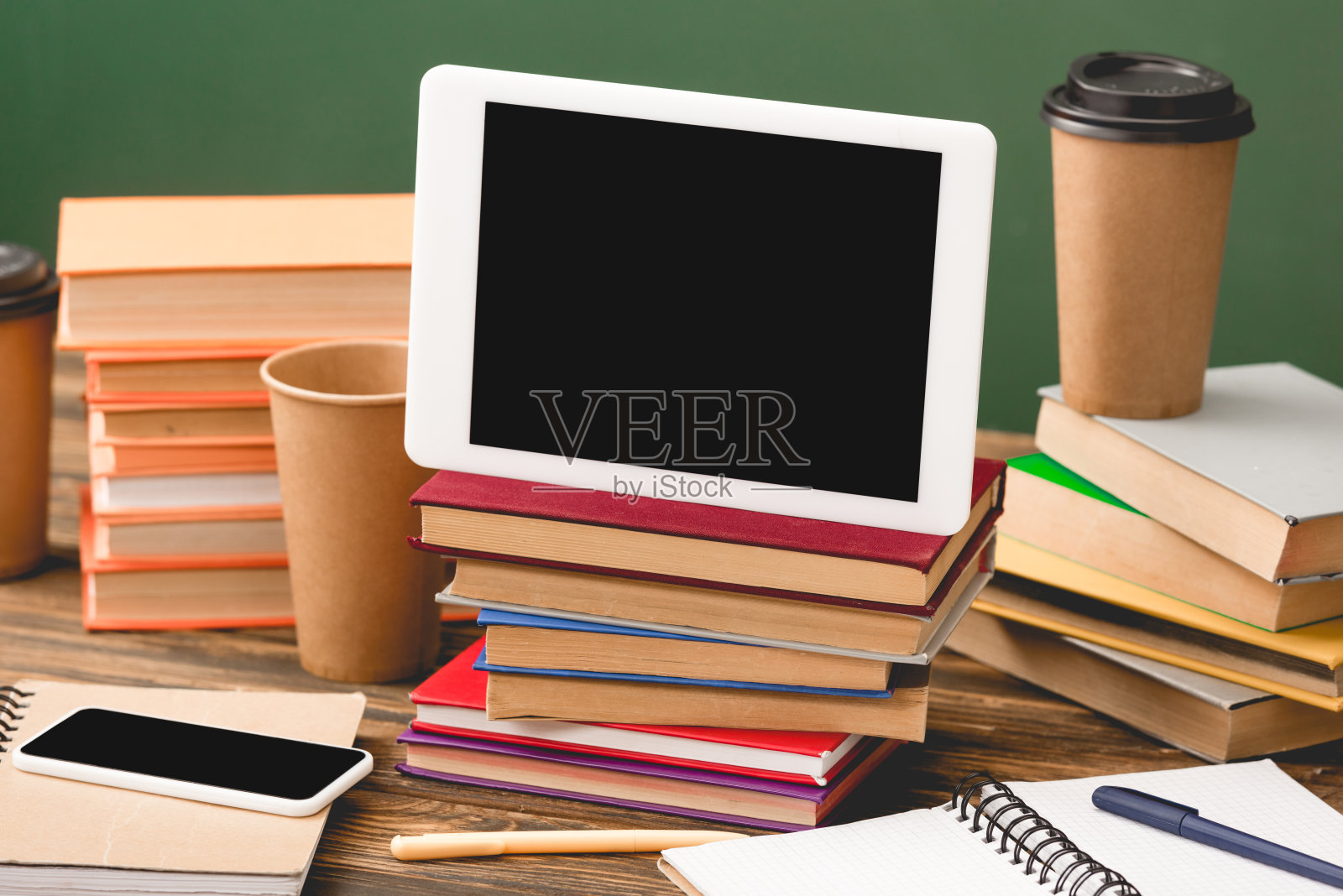 书籍、笔记本、笔、一次性杯子、智能手机和数字平板电脑的空白屏幕在木质表面隔离绿色照片摄影图片