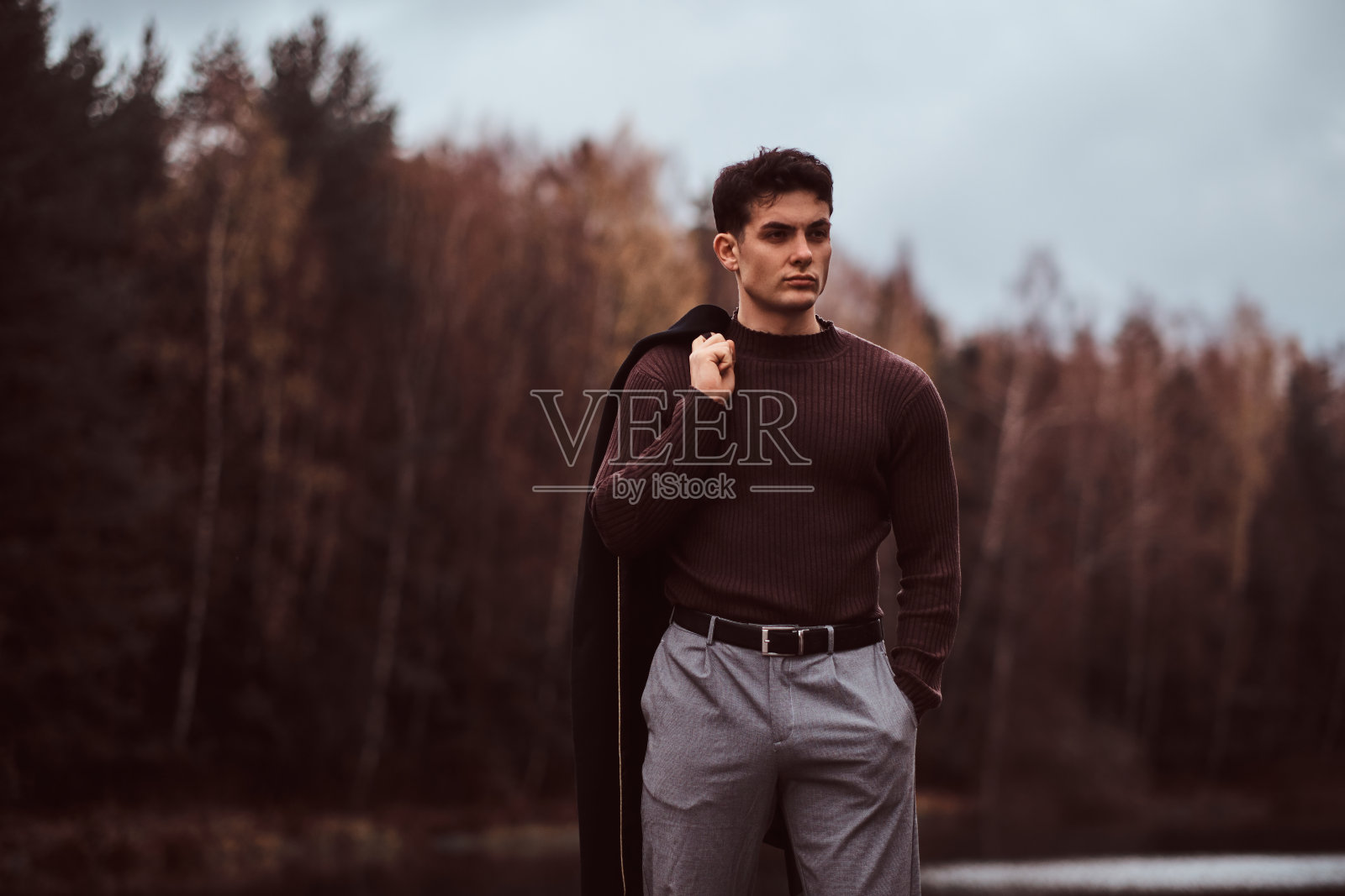 秋天的森林里，一个自信的年轻人在湖边。照片摄影图片