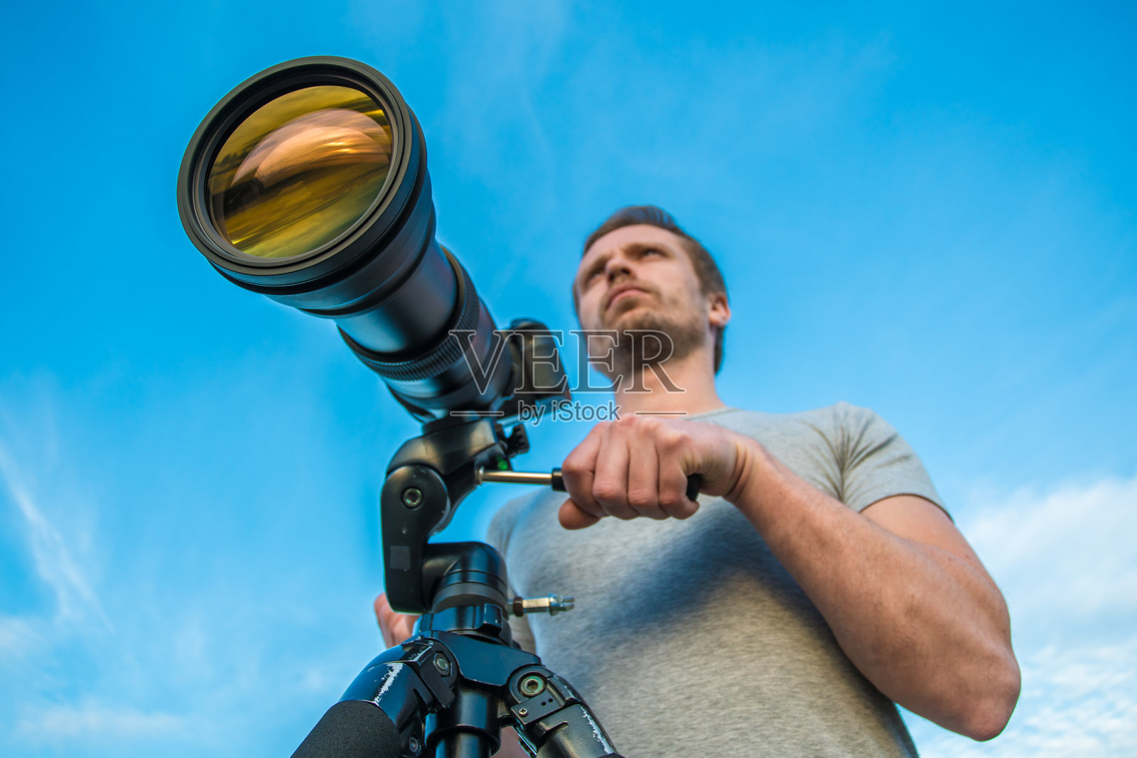 这个男人拿着相机站在蓝天的背景上照片摄影图片