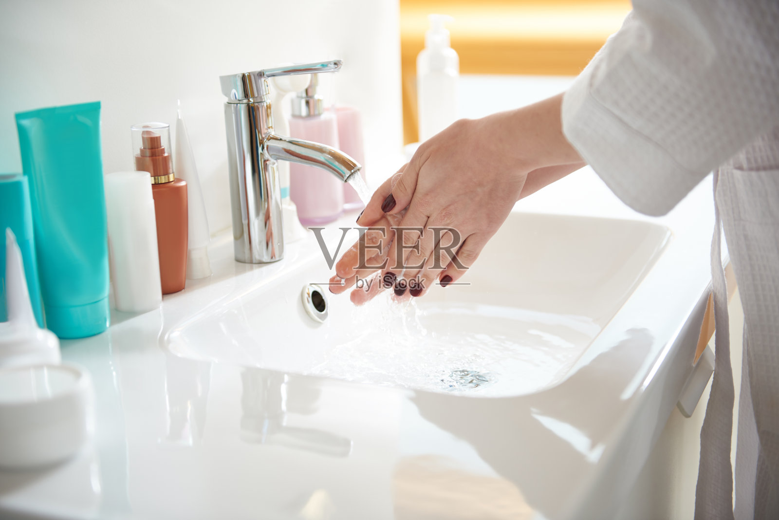 浴室的水槽和一个正在洗手的女人照片摄影图片