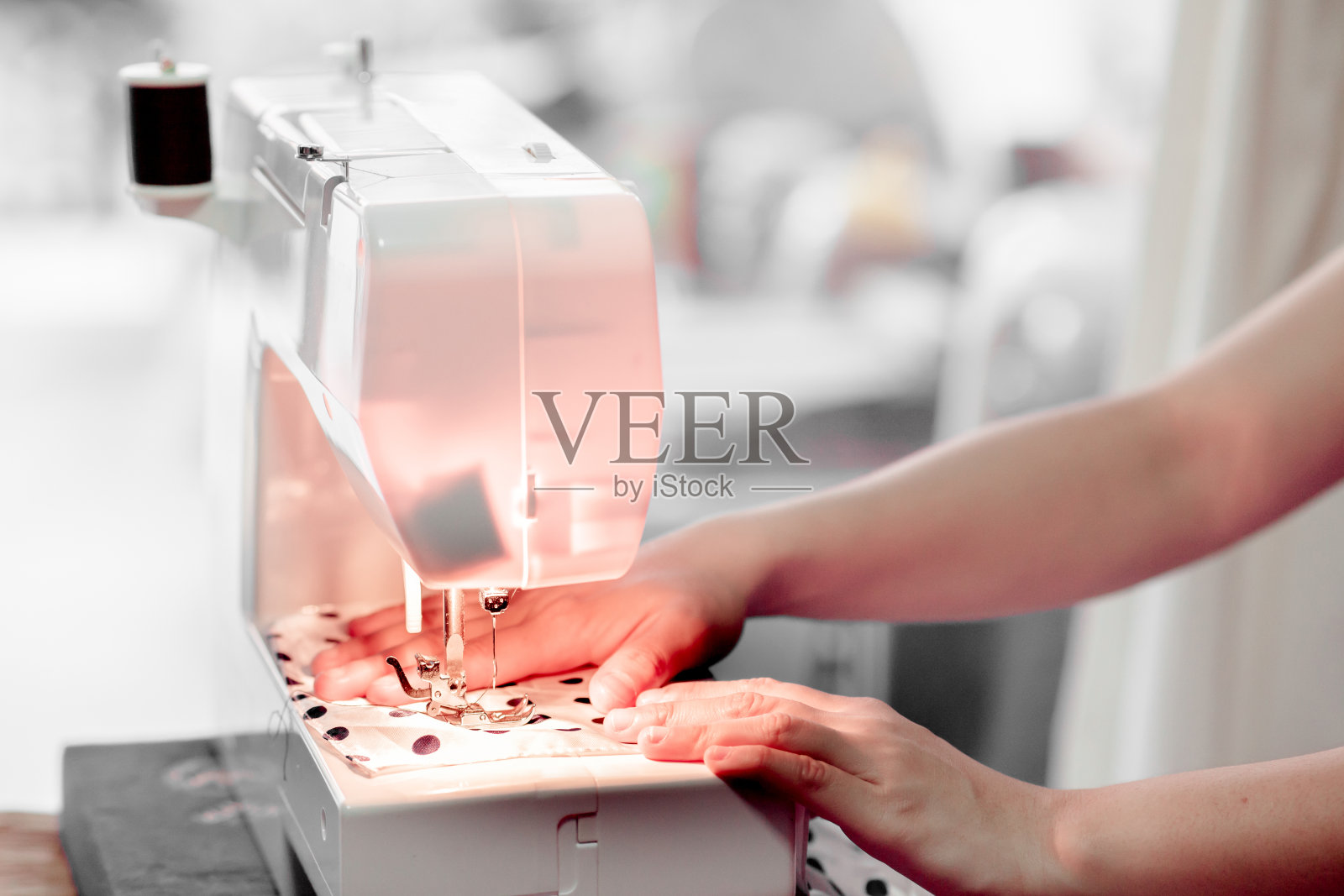 妇女的手在她的缝纫机和针后缝制织物的纺织阶段的缝补。裁剪过程照片摄影图片