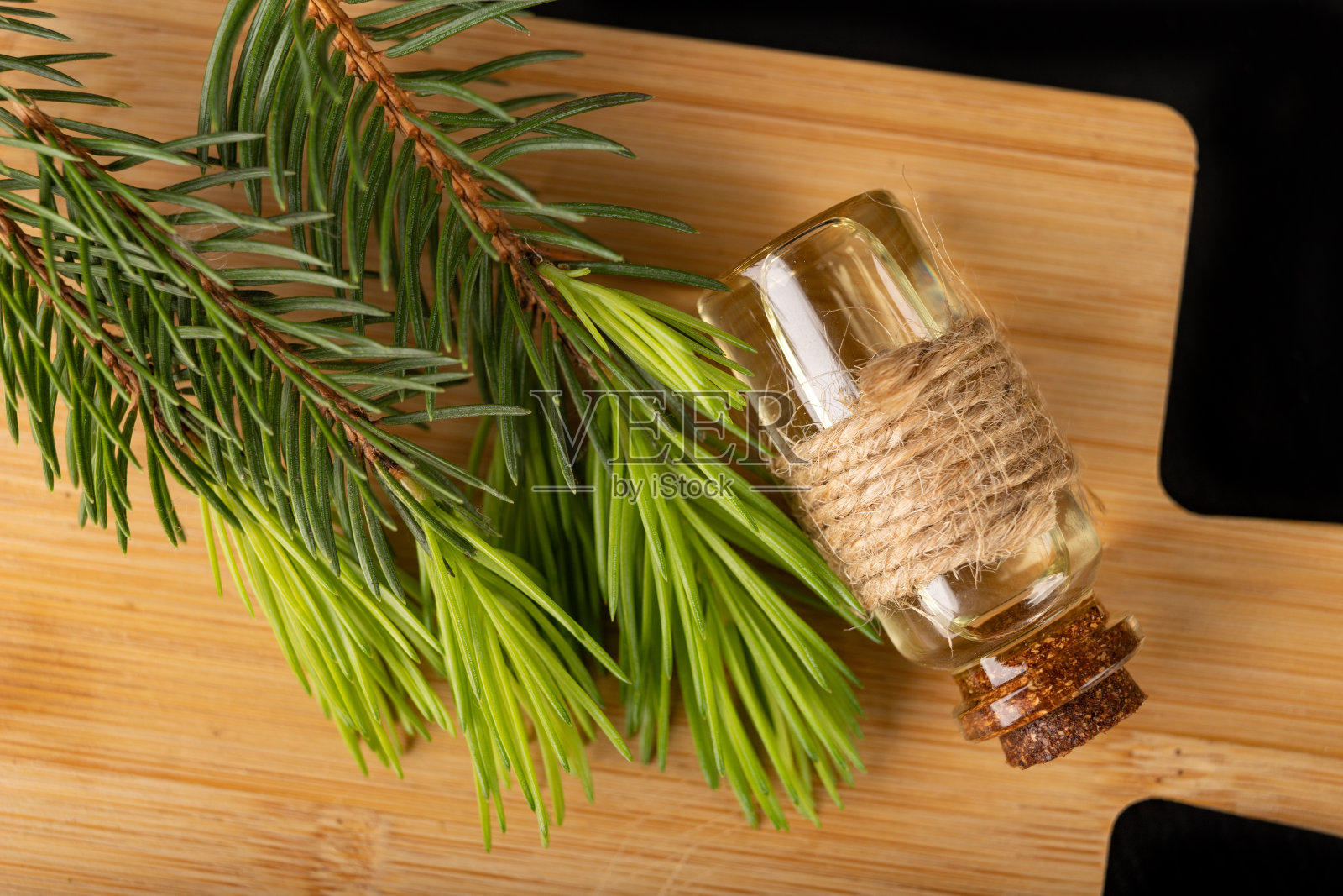 在玻璃盘中的云杉和油的幼芽。生态准备在木板上。黑暗的背景。照片摄影图片